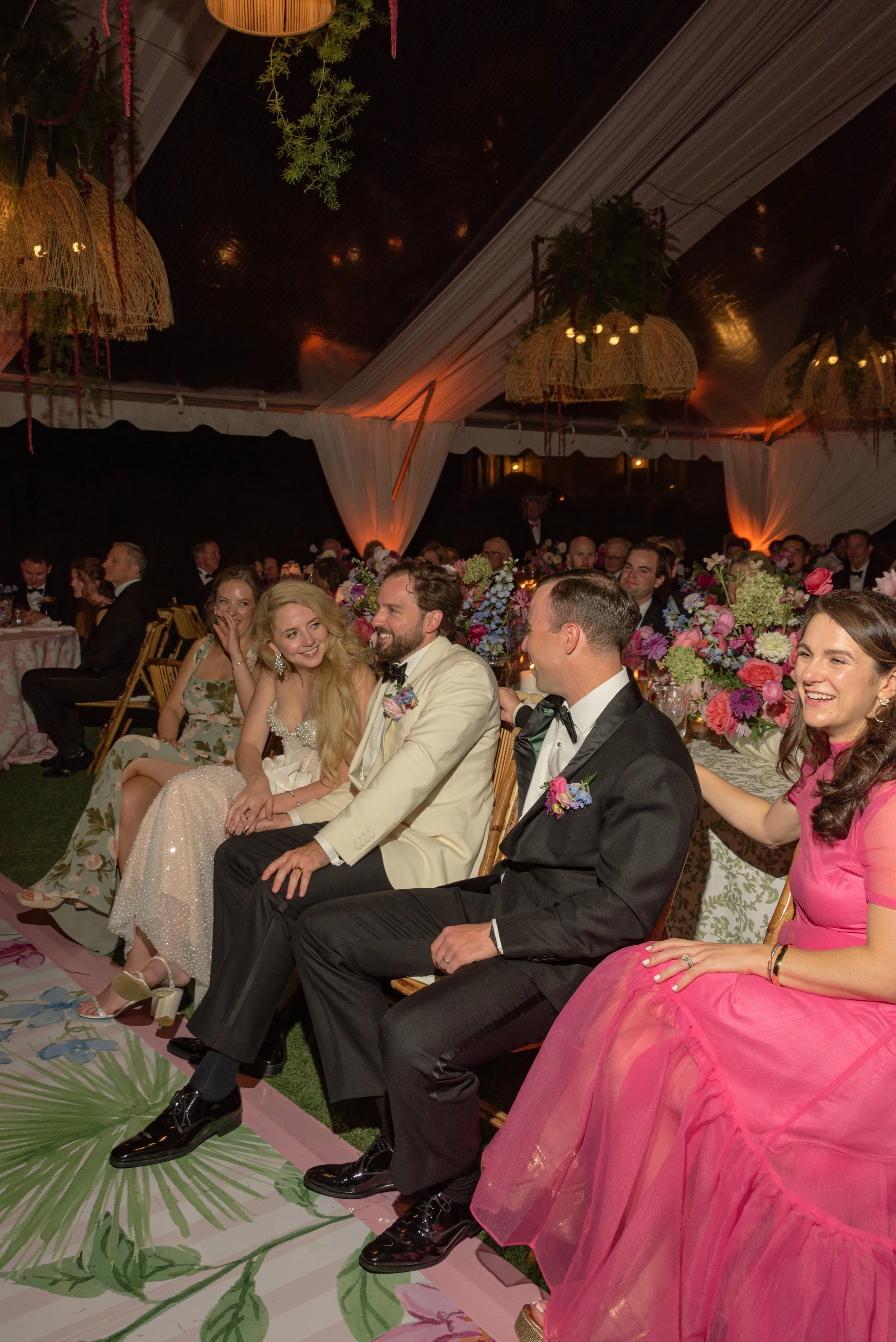 Katie and Trevor laugh with family members while listening to reception speeches.