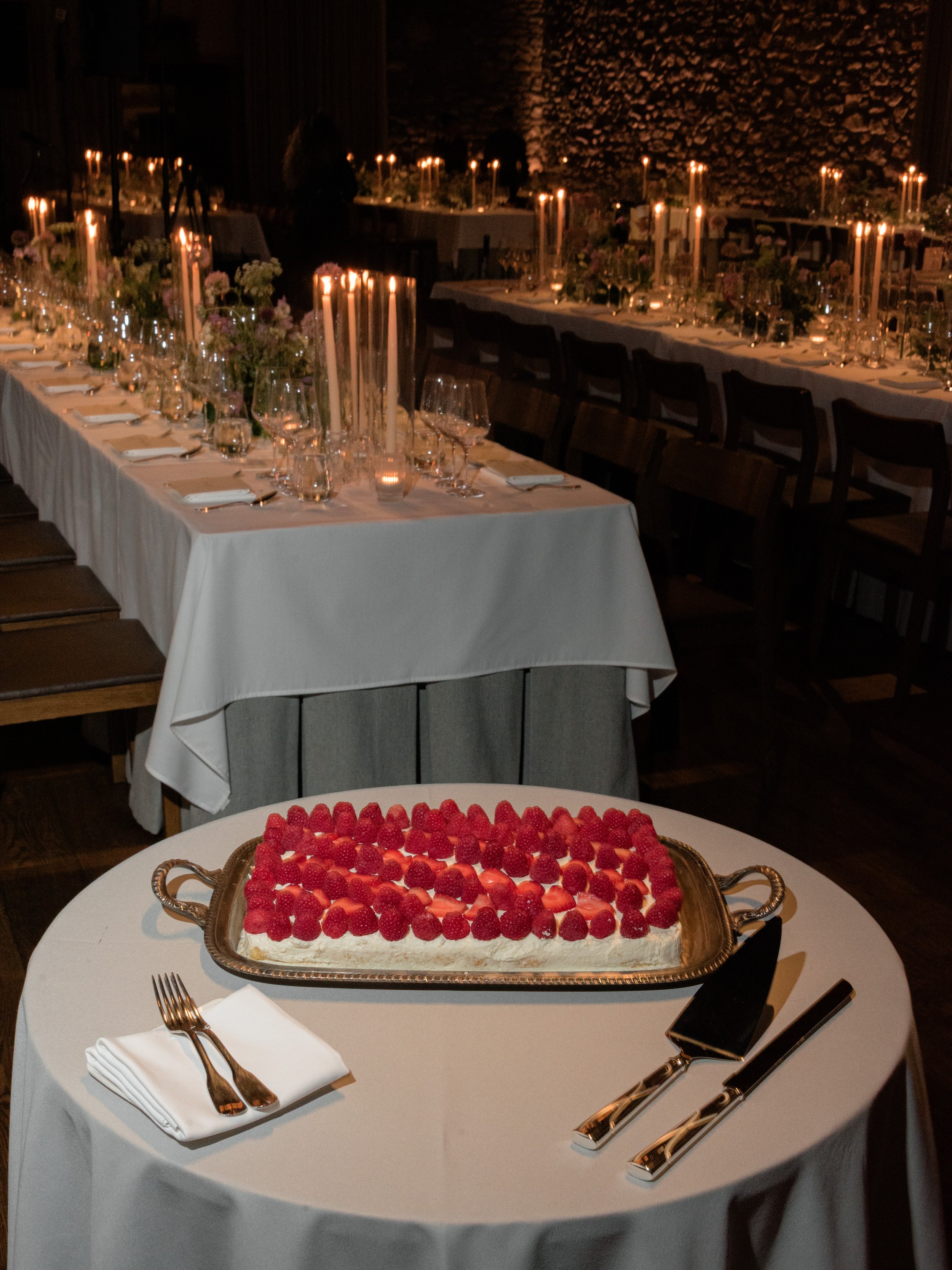 Red berry dessert presented beside the candlelit reception tables at Blue Hill at Stone Barns.