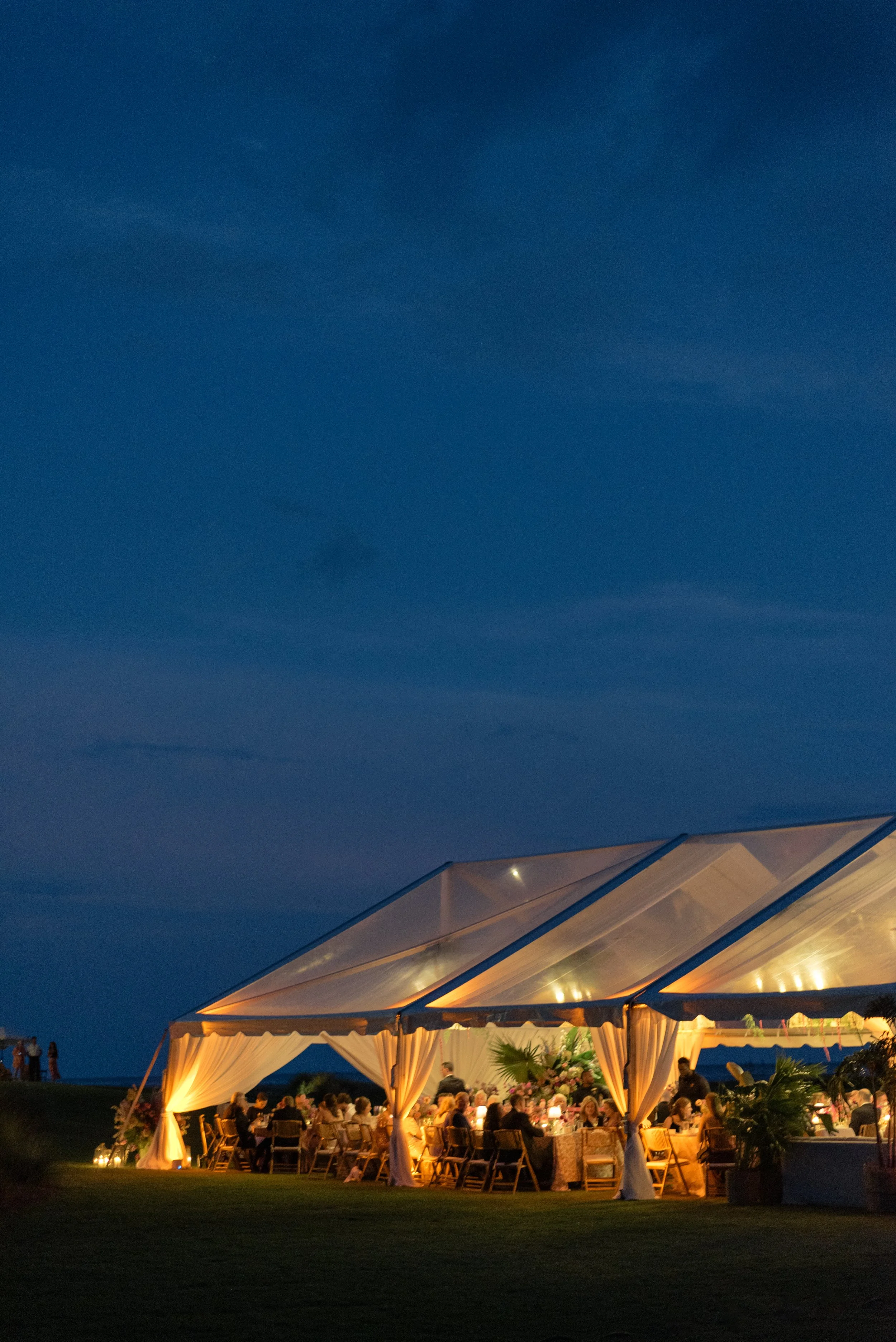Ocean Course reception tent glows against the dark coastal sky during the evening celebration.