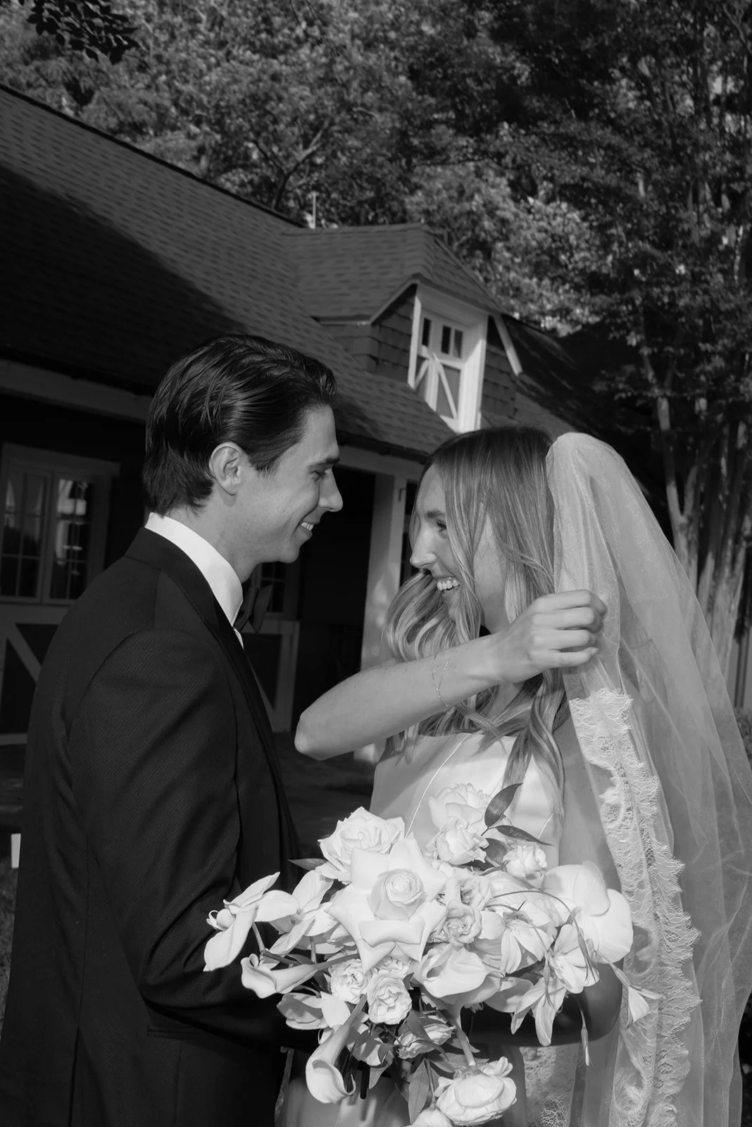Black-and-white close-up of the bride and groom kissing while holding a white bouquet at Goodstone Inn.