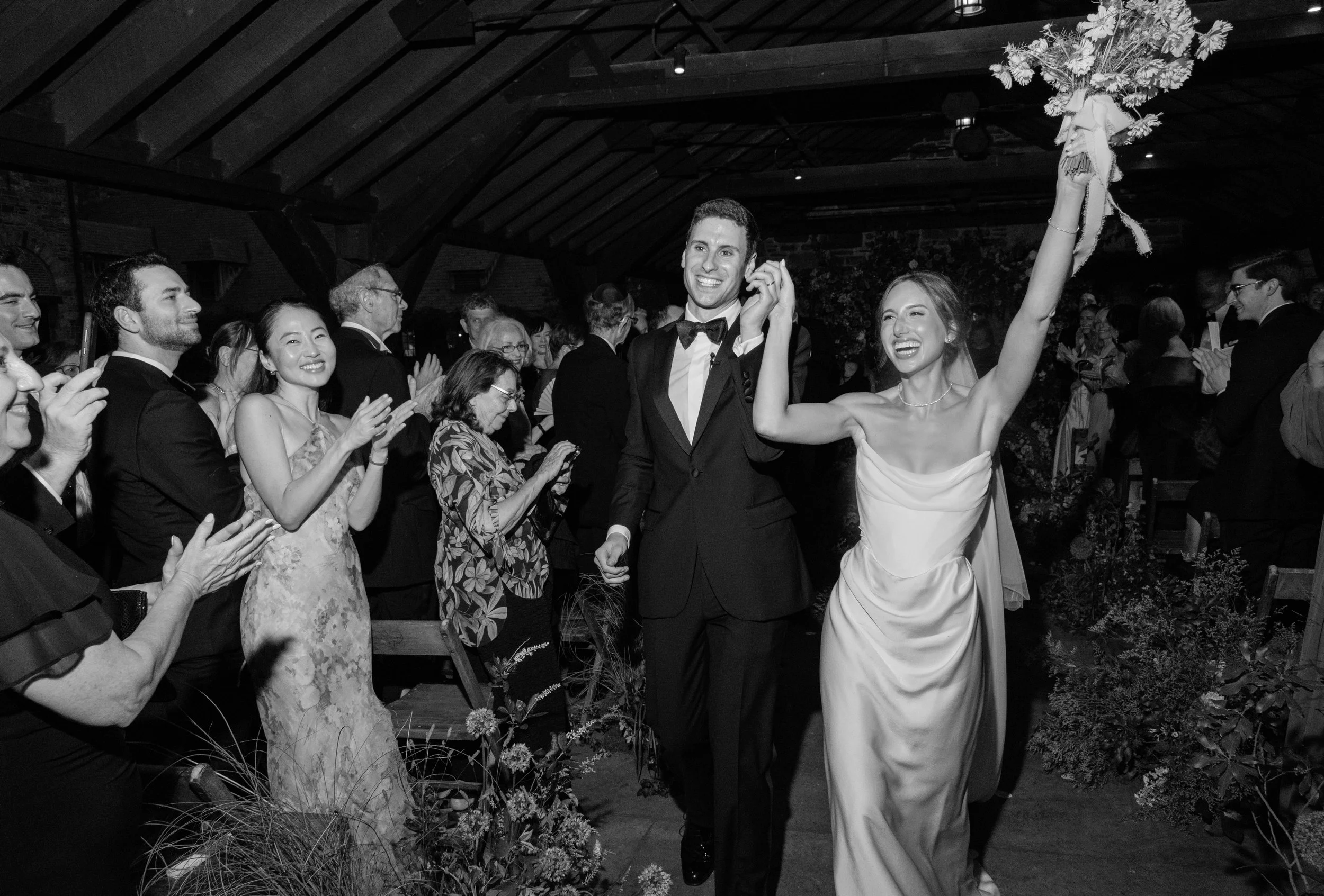 An editorial black and white photo of the bride and groom exiting their wedding ceremony in a frenzy.