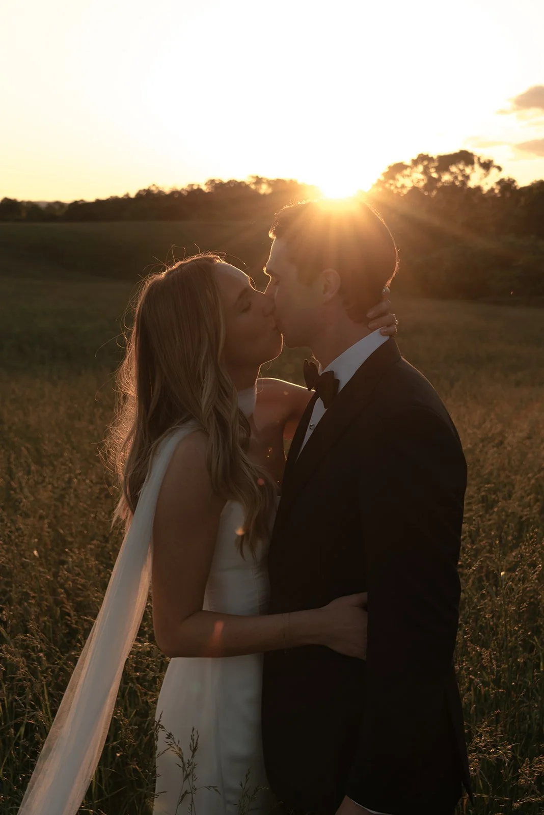 Bride and groom kissing in warm backlight at sunset at Goodstone Inn.