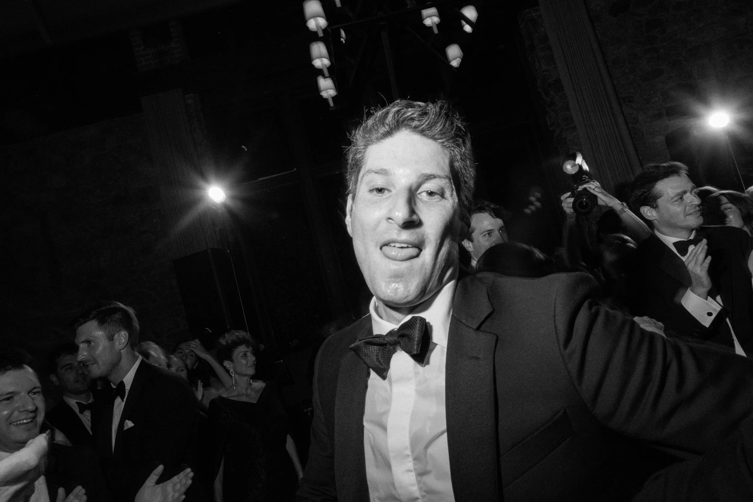 Black-and-white candid of Will's brother smiling directly toward the camera during the reception celebration.