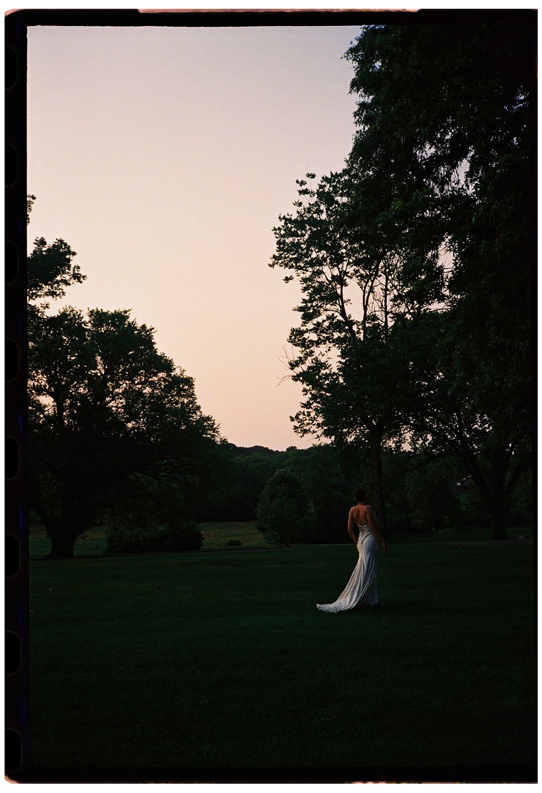 Bride standing alone in a wide garden landscape at a private estate wedding in Franklin, Tennessee, creating a cinematic editorial portrait that emphasizes scale, place, and emotion.