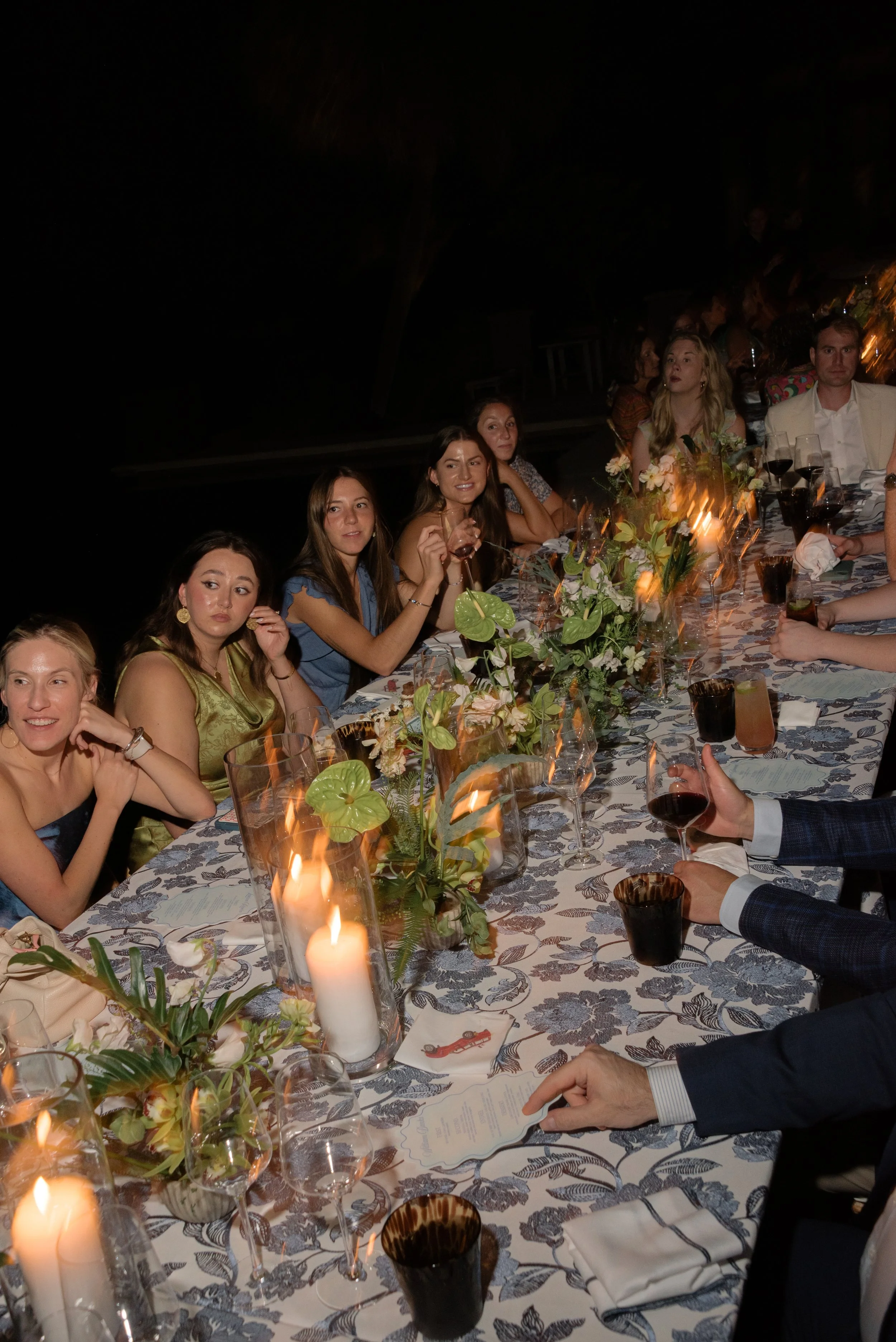 Guests enjoying an intimate rehearsal dinner surrounded by candles, floral arrangements, and thoughtfully designed tropical details.