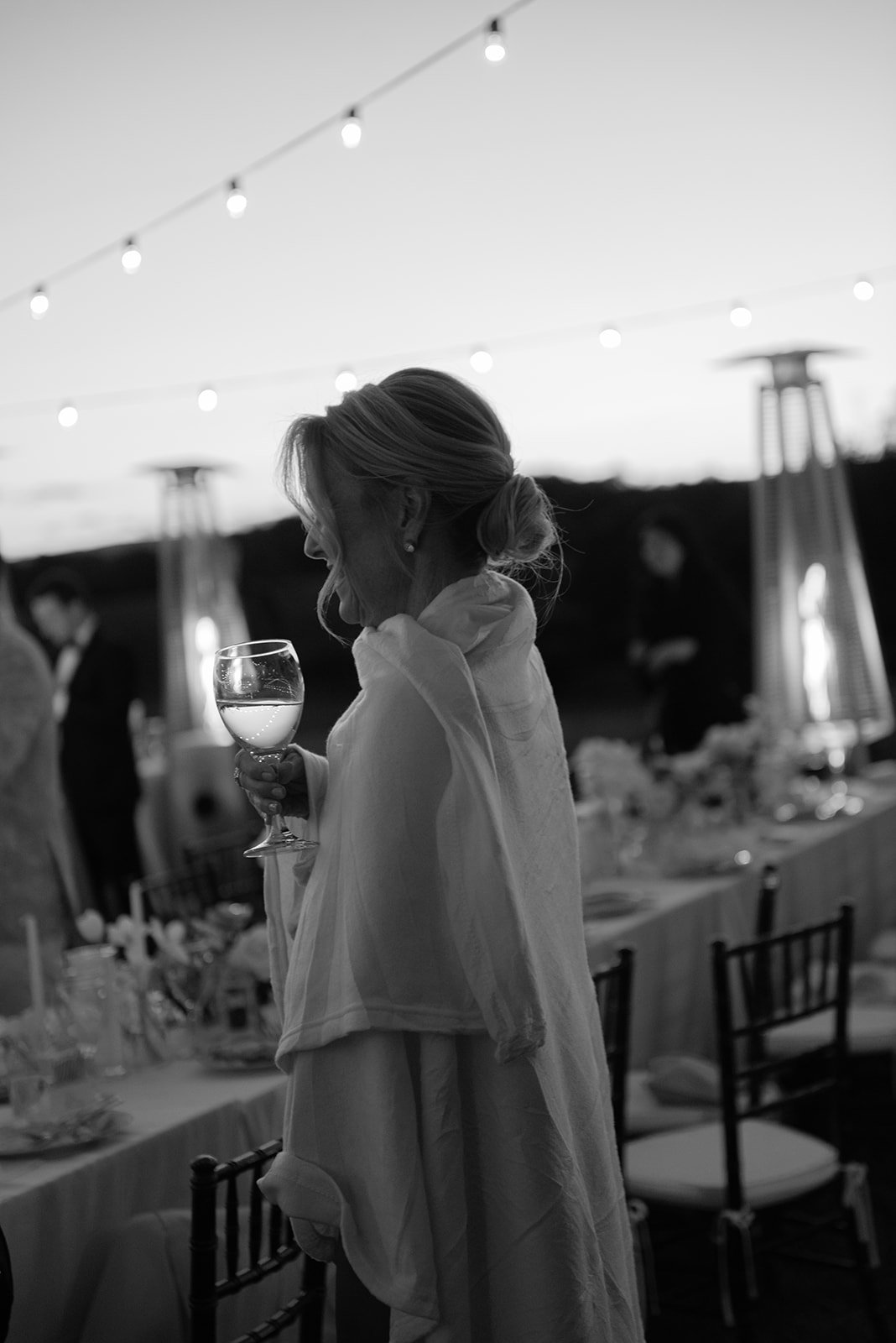 Black-and-white photograph of bride's mother wrapped in a cashmere blanket during the evening reception at Goodstone Inn.