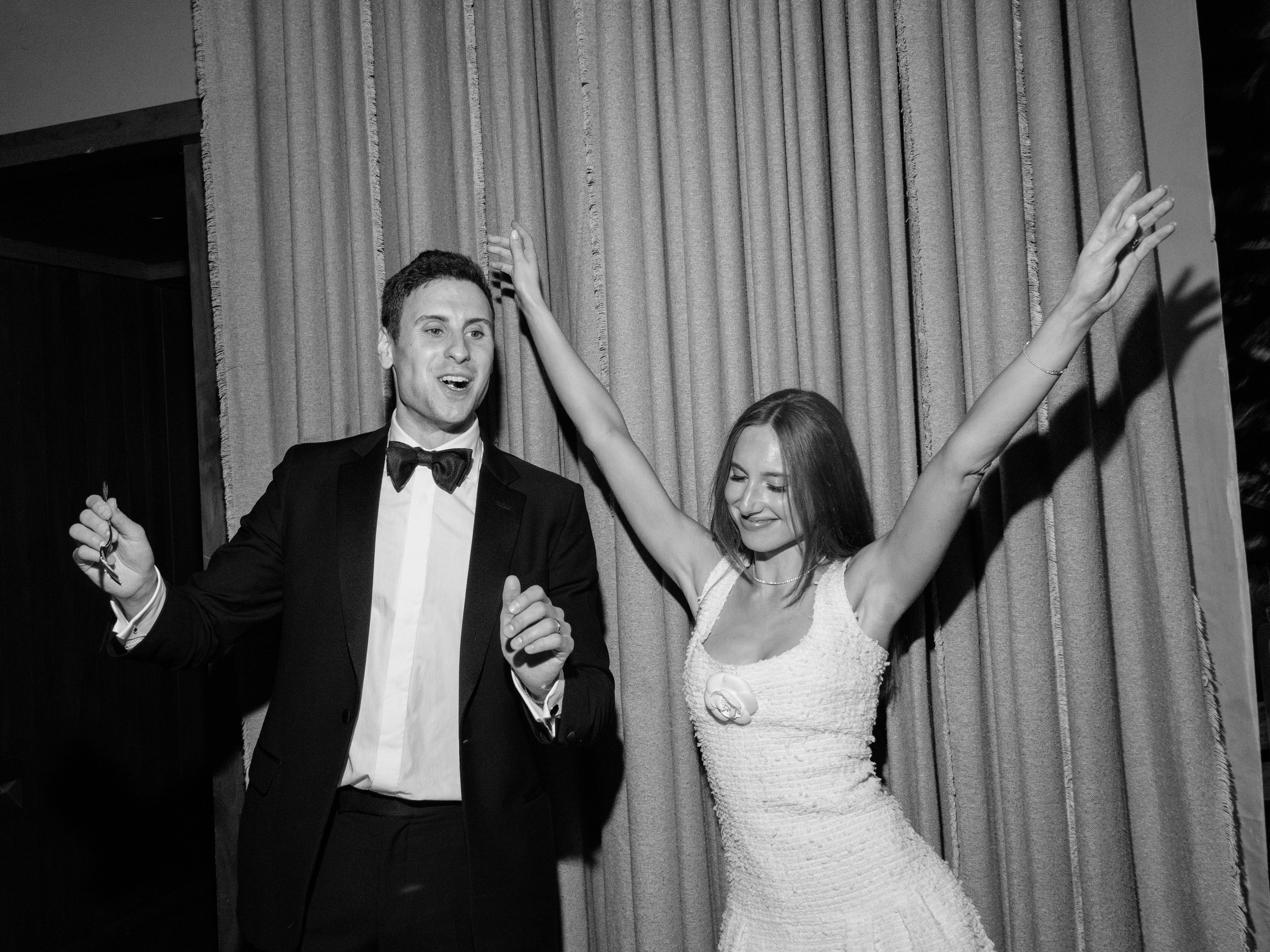 Black-and-white photograph of Jennie and Will celebrating together after cutting their wedding cake.