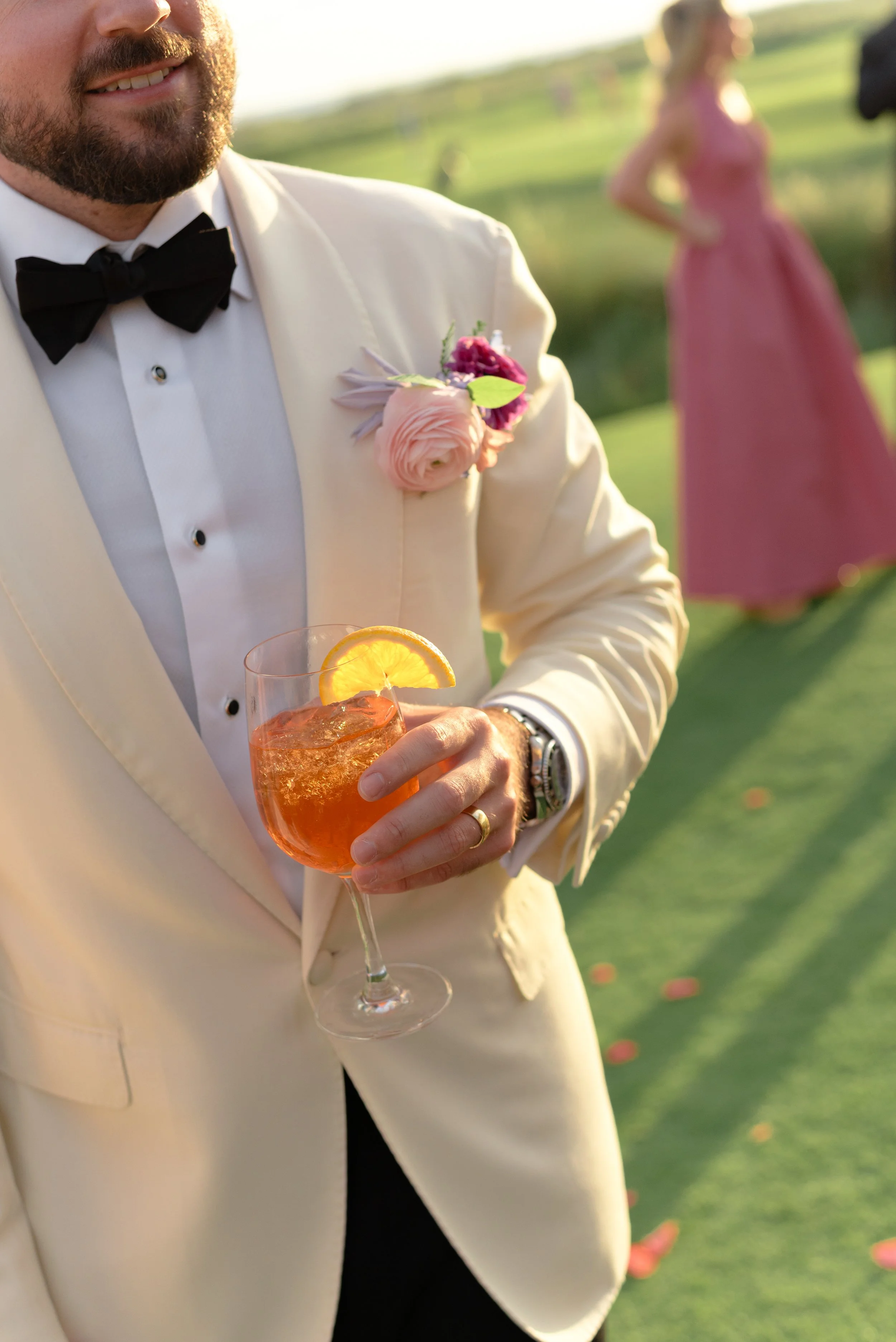 Trevor holds an Aperol Spritz cocktail against his white dinner jacket during cocktail hour at The Ocean Course.