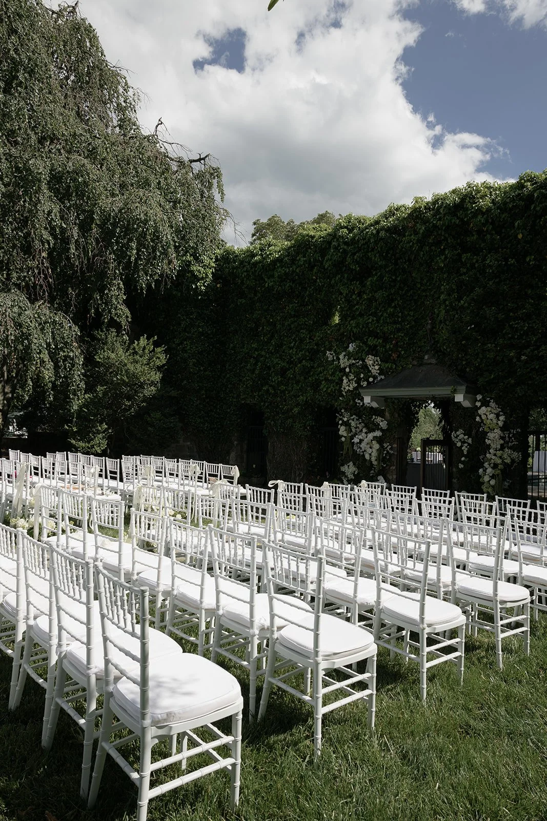 Rows of white wedding ceremony chairs arranged beside lush greenery at Goodstone Inn in Virginia.