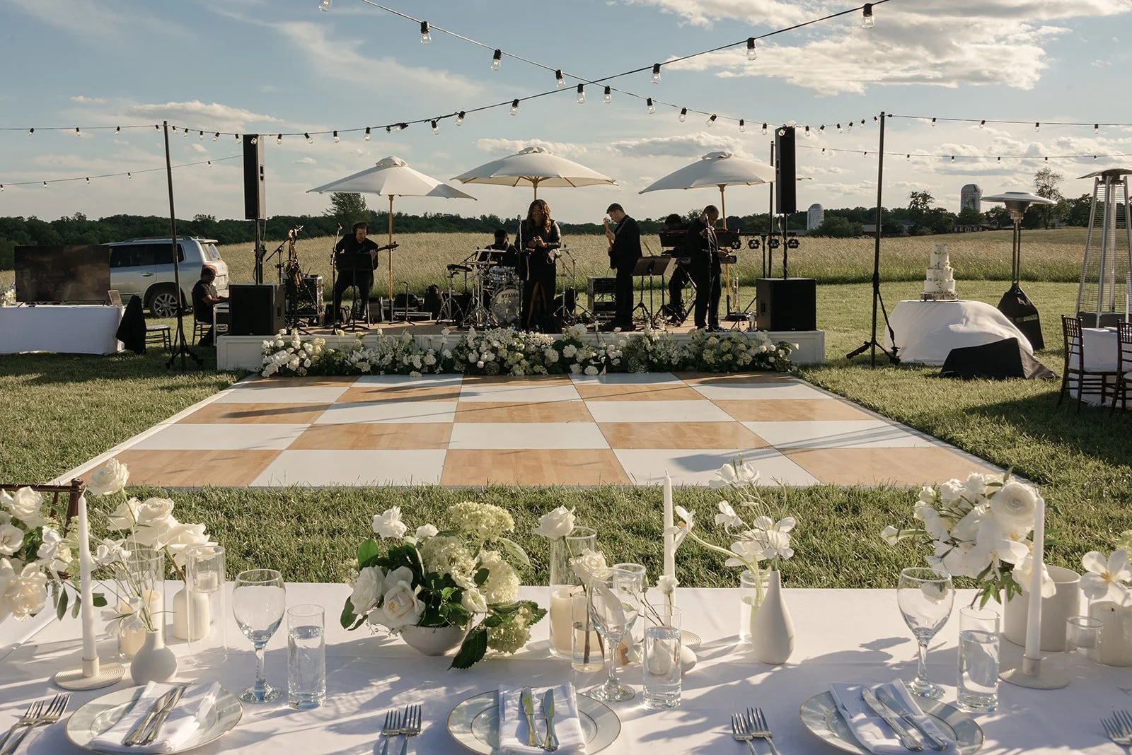 Checkerboard wedding dance floor and reception tables arranged beneath string lights in the Goodstone Inn Hayfield.