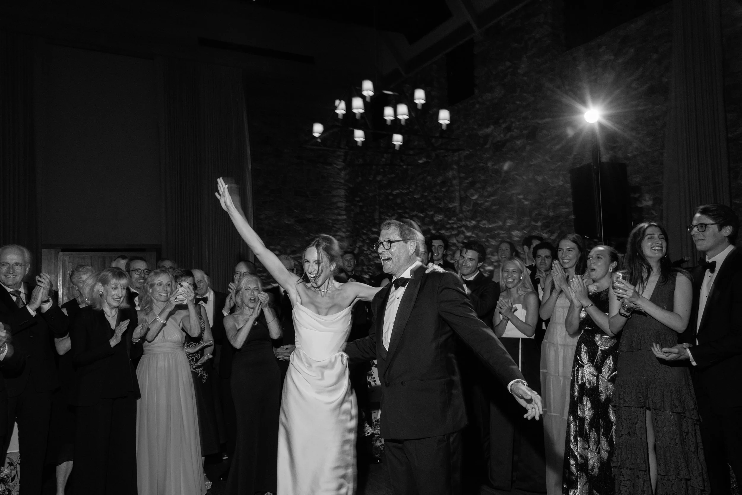 Black-and-white reception photograph of Jennie and her father surrounded by dancing guests and raised hands.