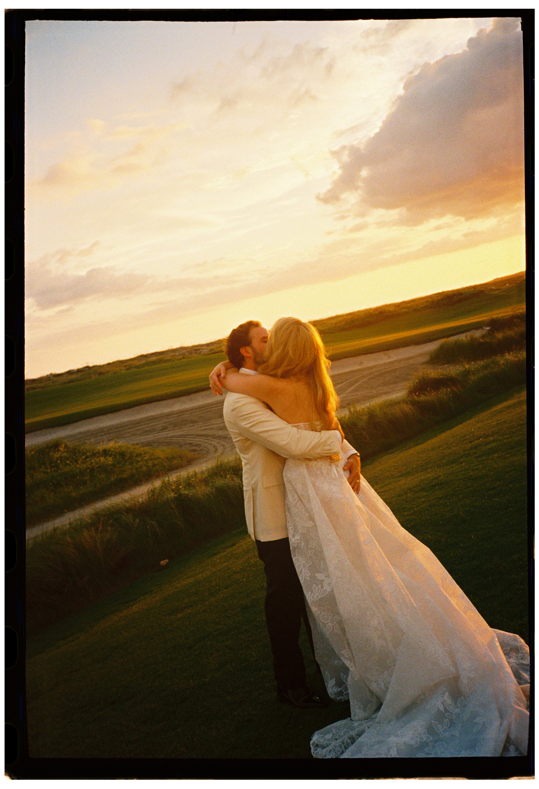 Film photograph of the bride and groom embracing beneath a dramatic golden sunset on Kiawah Island.