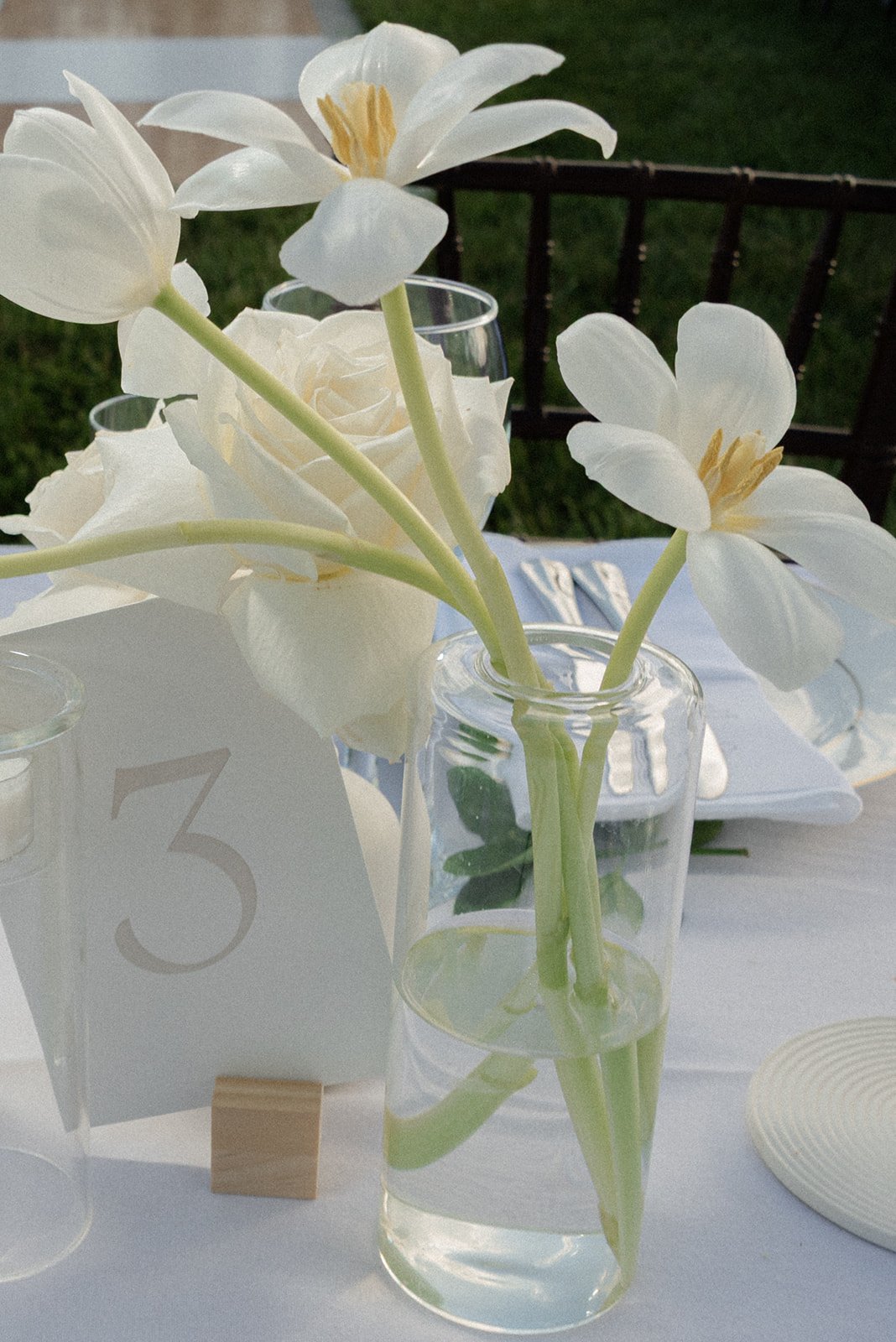 White flower stems arranged in a clear glass vase beside a table number at Goodstone Inn.