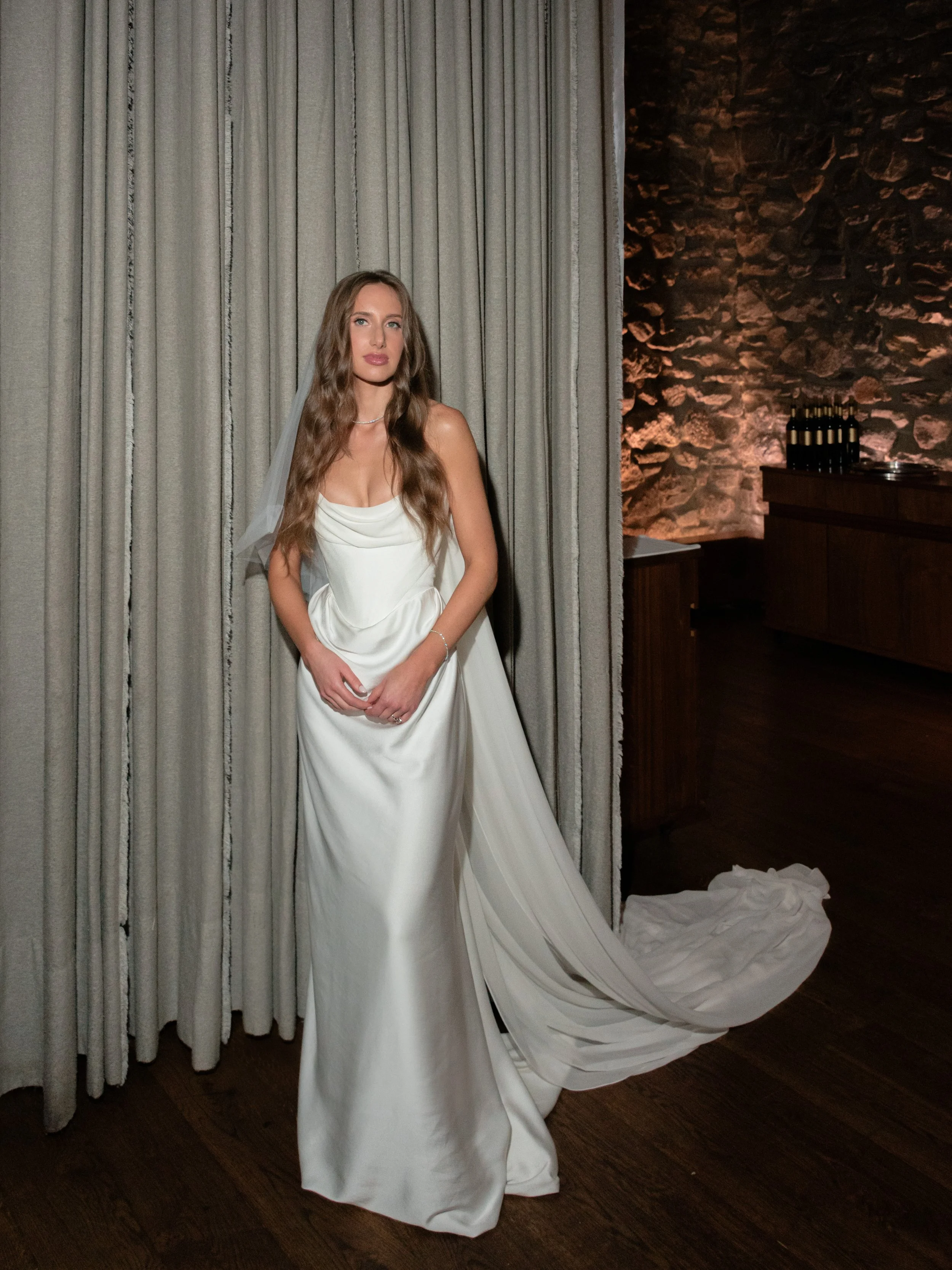 The bride wears Vivienne Westwood and poses with the floor-to-ceiling curtains inside the dining hall at Blue Hill at Stone Barns. 