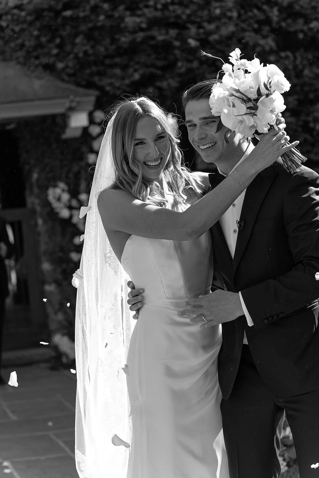 Black-and-white detail of the bride’s bouquet and gown beside the groom after their Goodstone Inn ceremony.