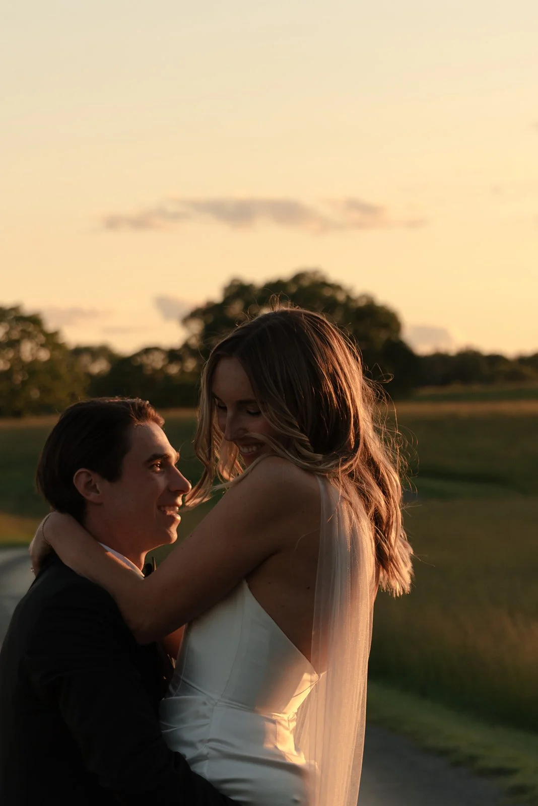 Bride and groom sharing an intimate moment in warm sunset light in the Hayfield at Goodstone Inn.