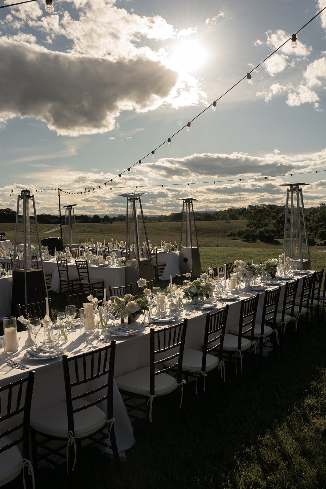 Long al fresco reception table beneath string lights and a dramatic spring sky at Goodstone Inn.