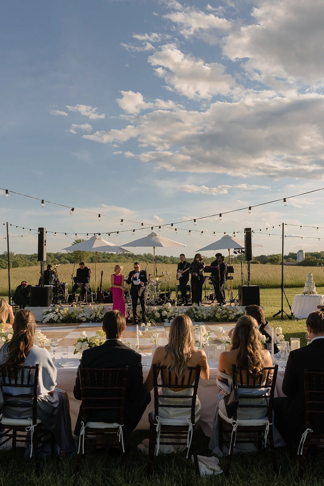 Outdoor wedding reception beneath string lights and a dramatic blue sky in the Hayfield at Goodstone Inn.
