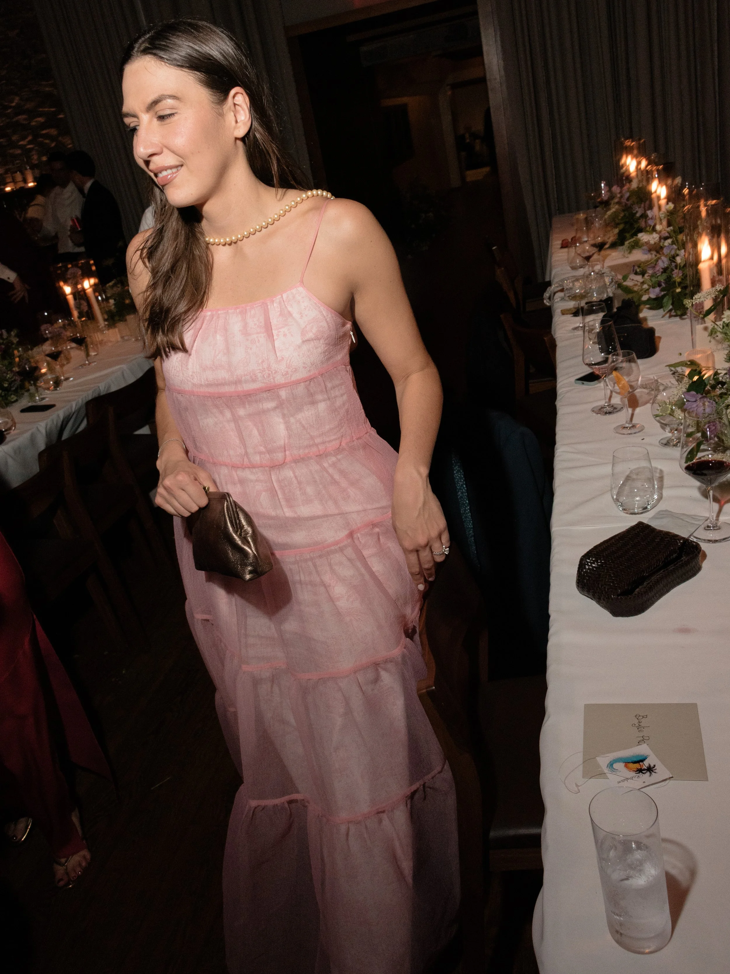 Wedding guest in a pink evening dress moving through the candlelit reception at Blue Hill at Stone Barns.