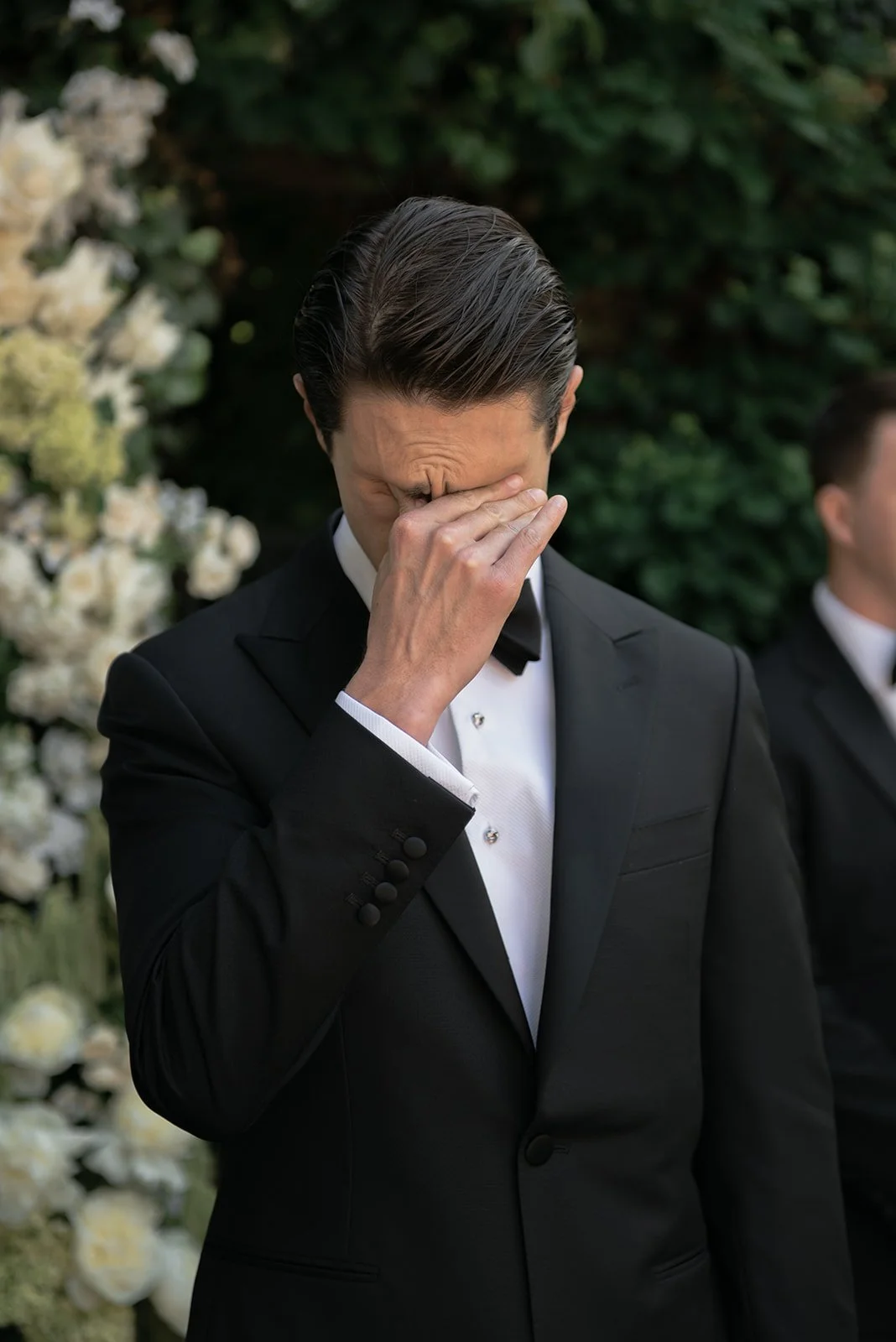 Emotional groom in a black tuxedo wiping his eyes during an outdoor wedding ceremony at Goodstone Inn in Virginia.