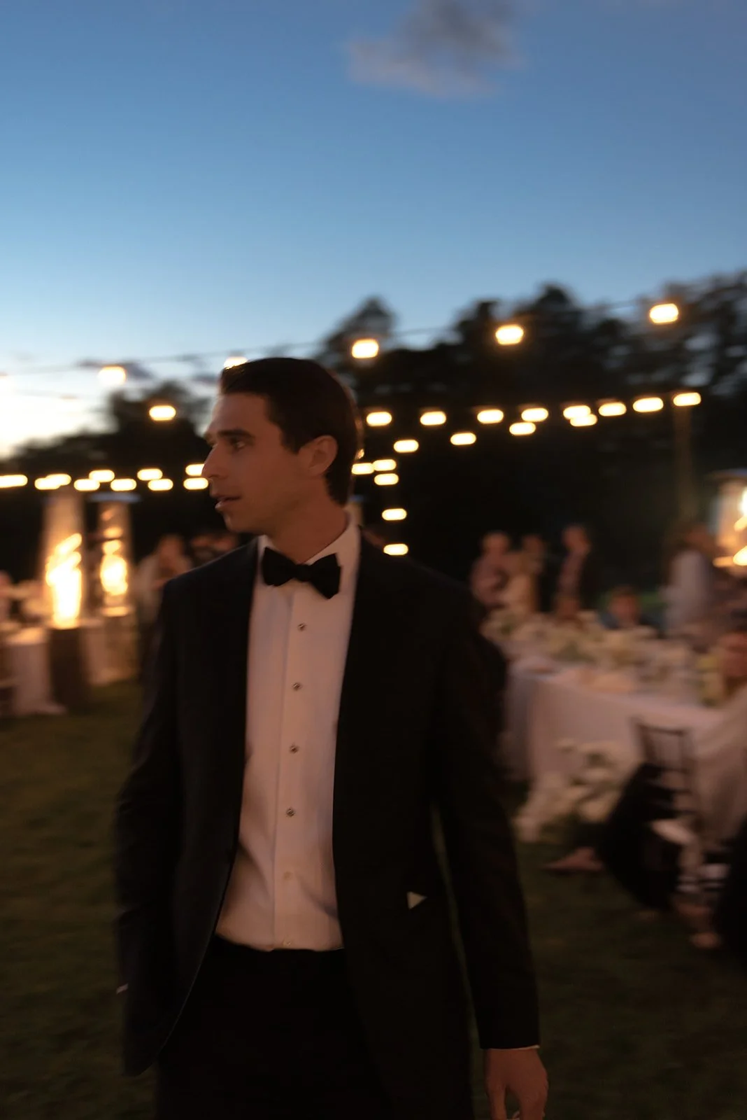 Groom moves beneath string lights during the outdoor reception at Goodstone Inn.