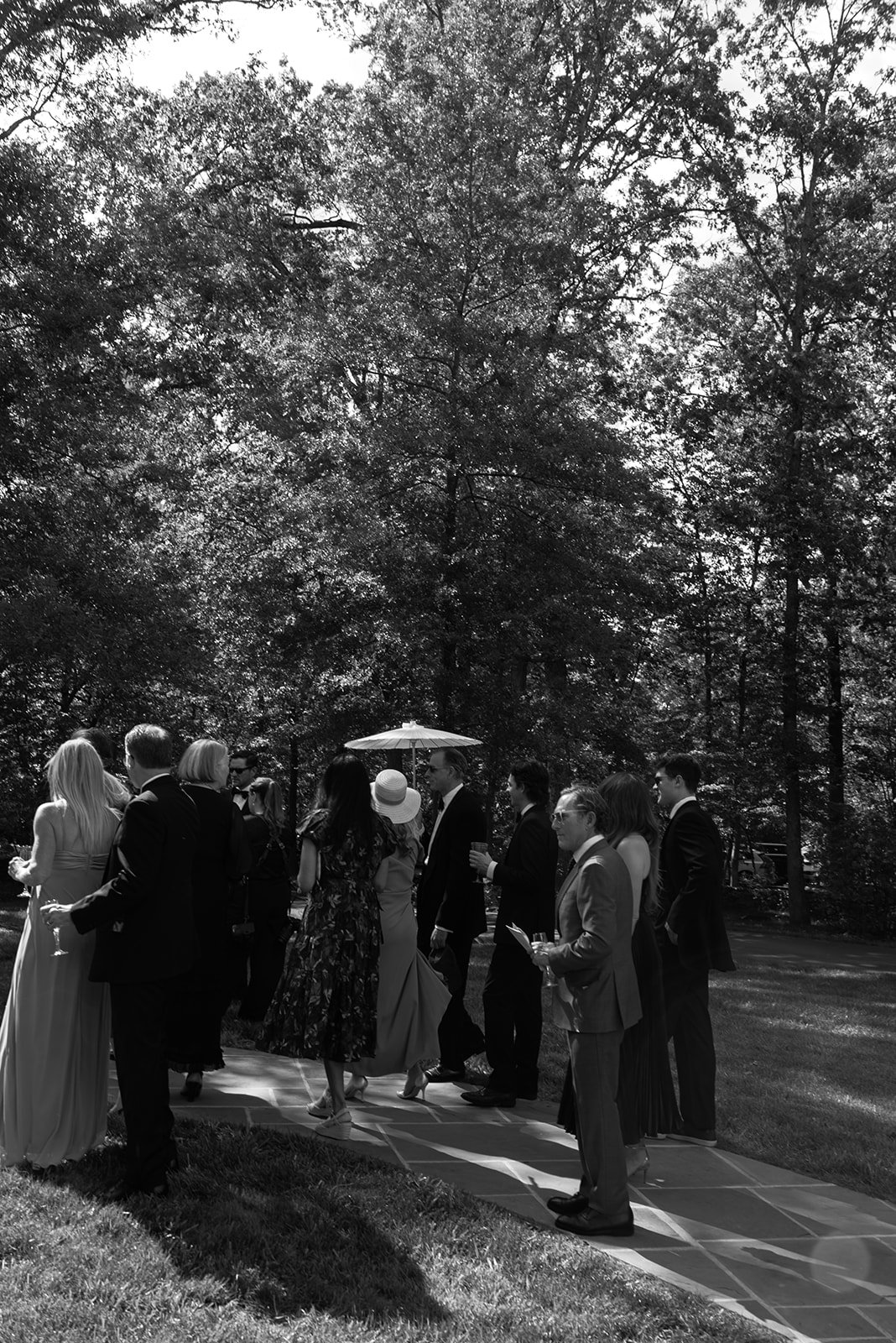 Black-and-white photograph of guests gathering beneath mature trees before a wedding ceremony at Goodstone Inn.
