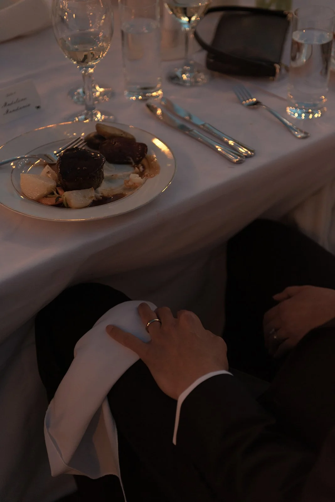 Close-up of the groom’s hand and new wedding band resting on his knee during the evening reception at Goodstone Inn.