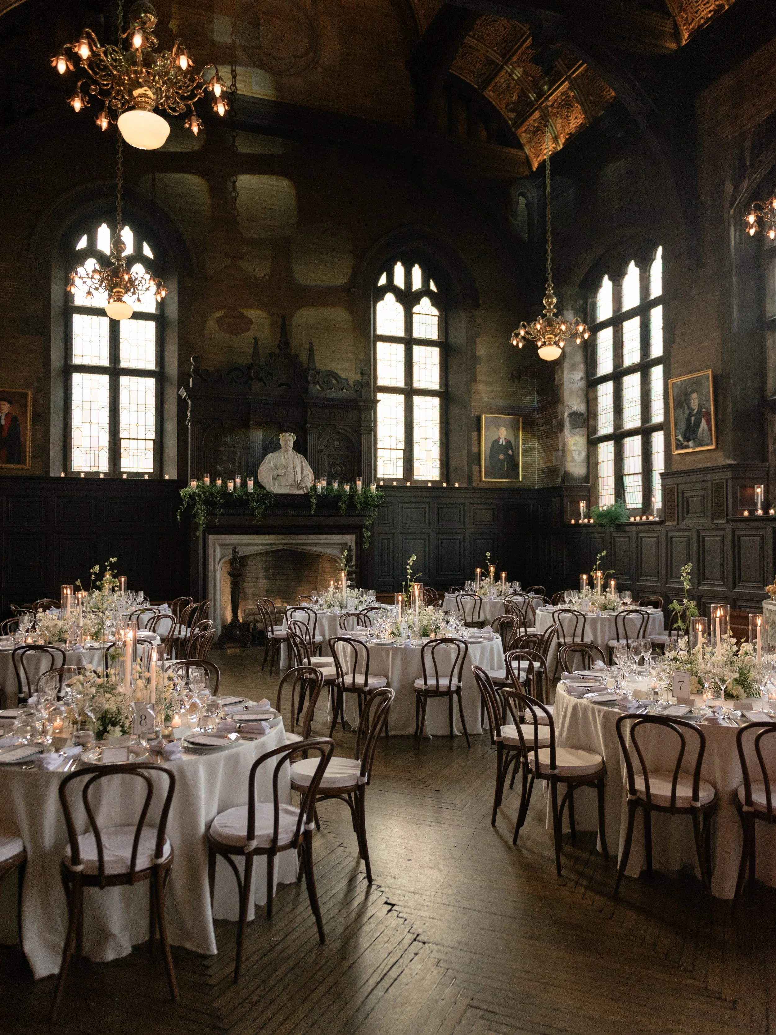 The historic wedding reception ballroom of the Highline Hotel and Chelsea Square set with round dinner tables, candlelight, and dramatic architectural details designed by Sarah Brennan Events.