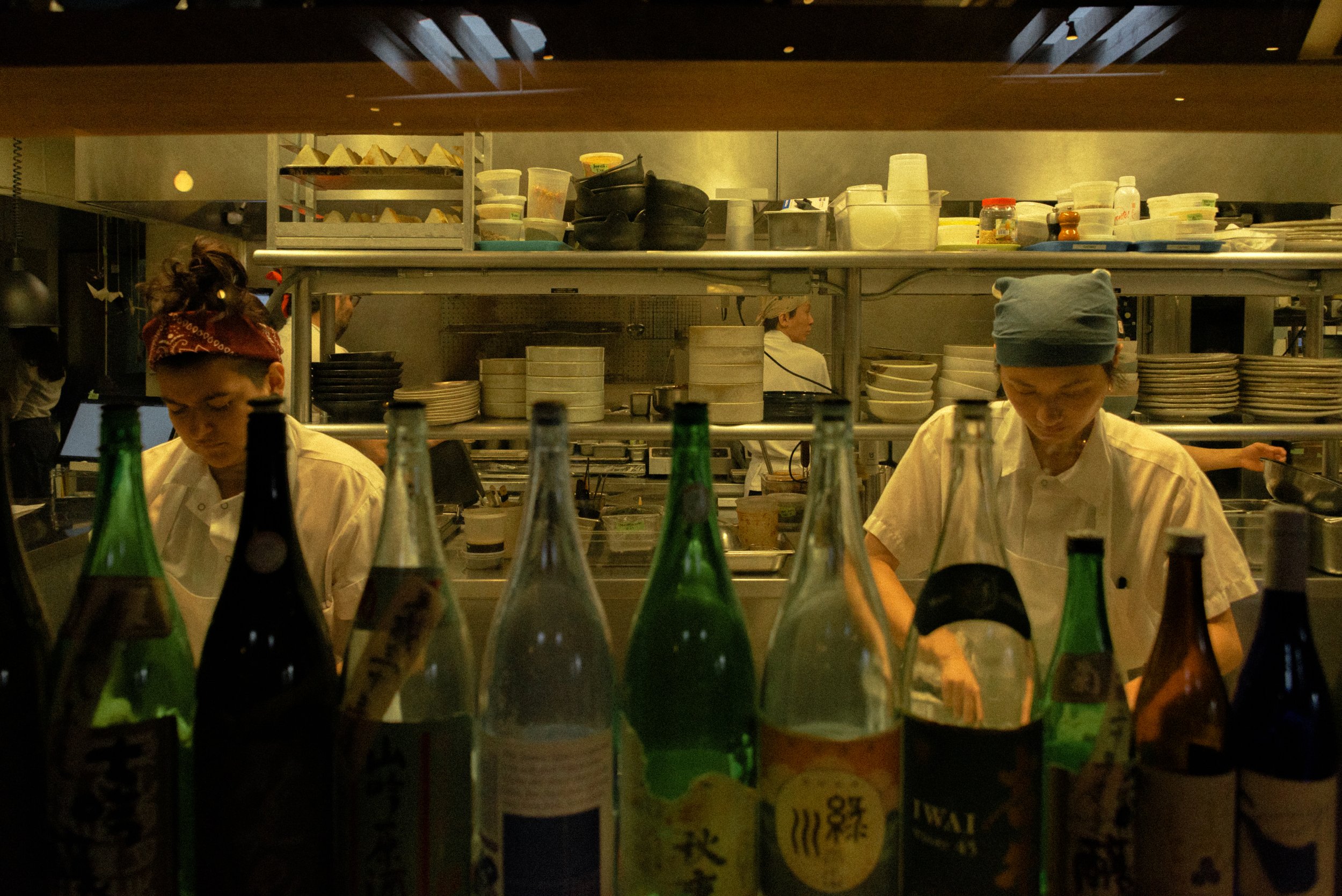 Interior photograph of a restaurant kitchen and chefs with curated bottles and architectural details at Rule of Thirds Brooklyn.