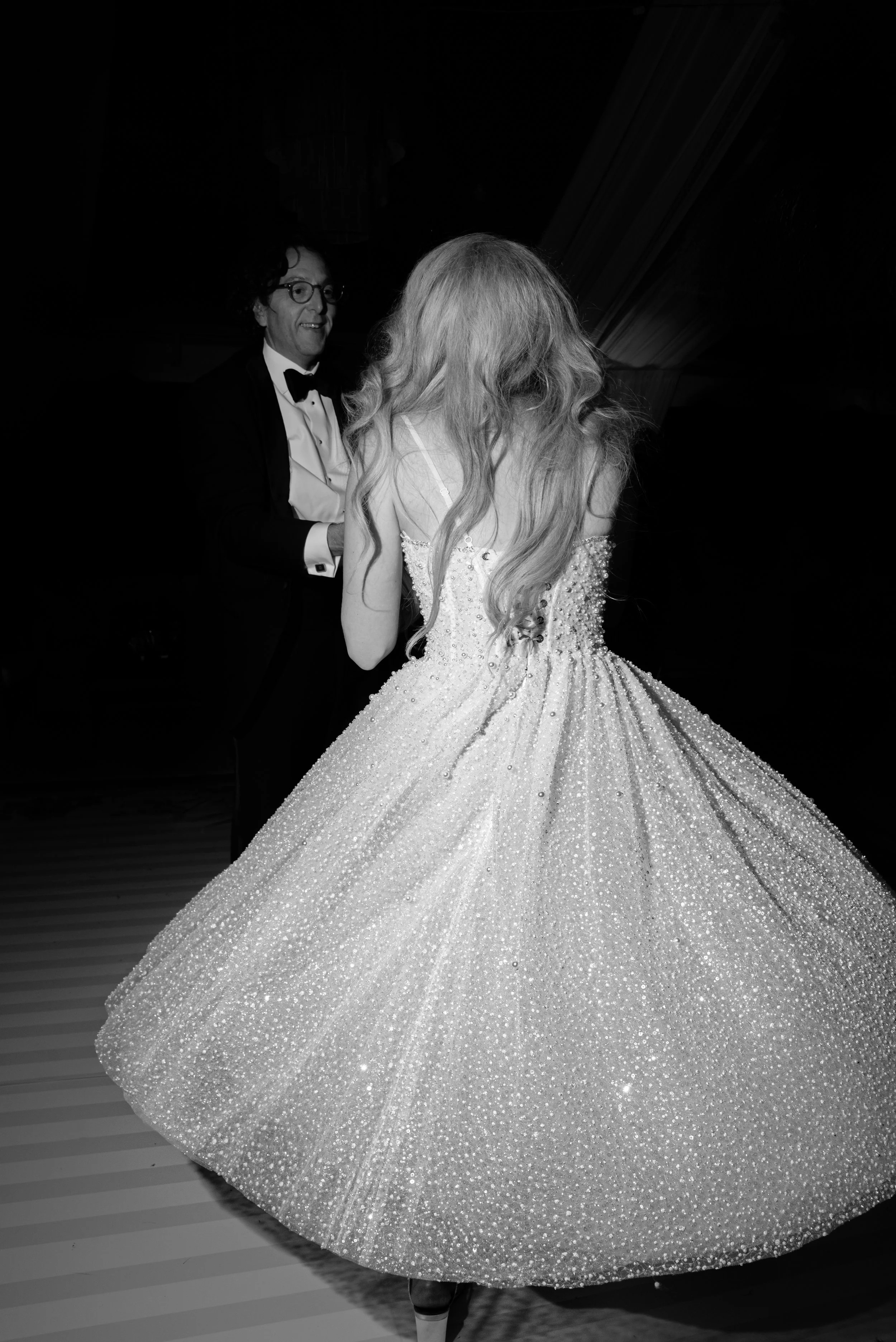 Black-and-white photograph of Katie spinning in her sparkling Milla Nova reception dress on the dance floor.