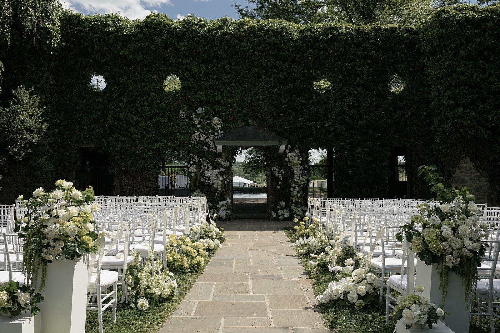 Ivy Wall ceremony aisle lined with white chairs and ivory flowers at Goodstone Inn in Middleburg, Virginia.