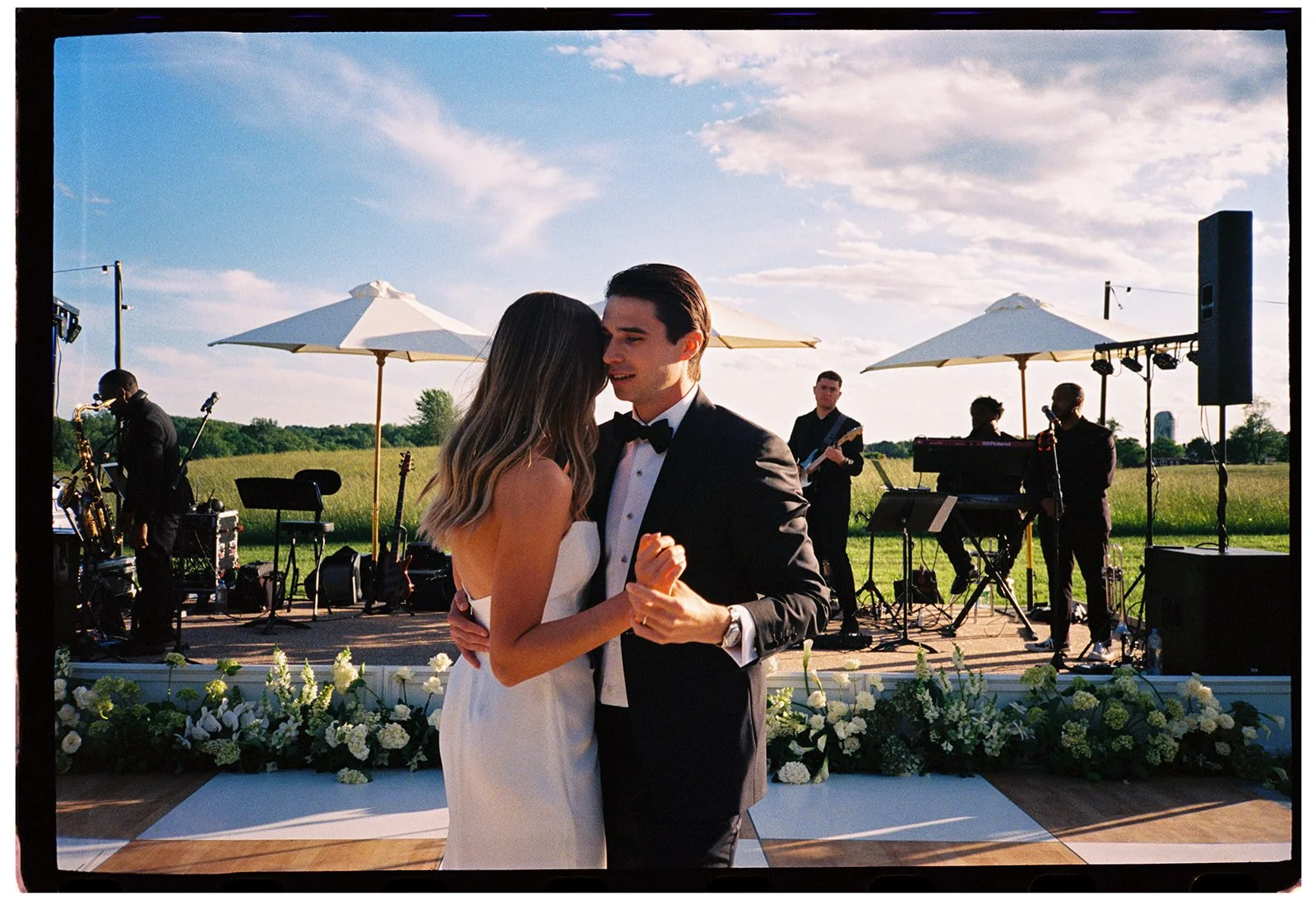 Bride and groom dancing together on the outdoor dance floor with a live band behind them at Goodstone Inn captured on film. 