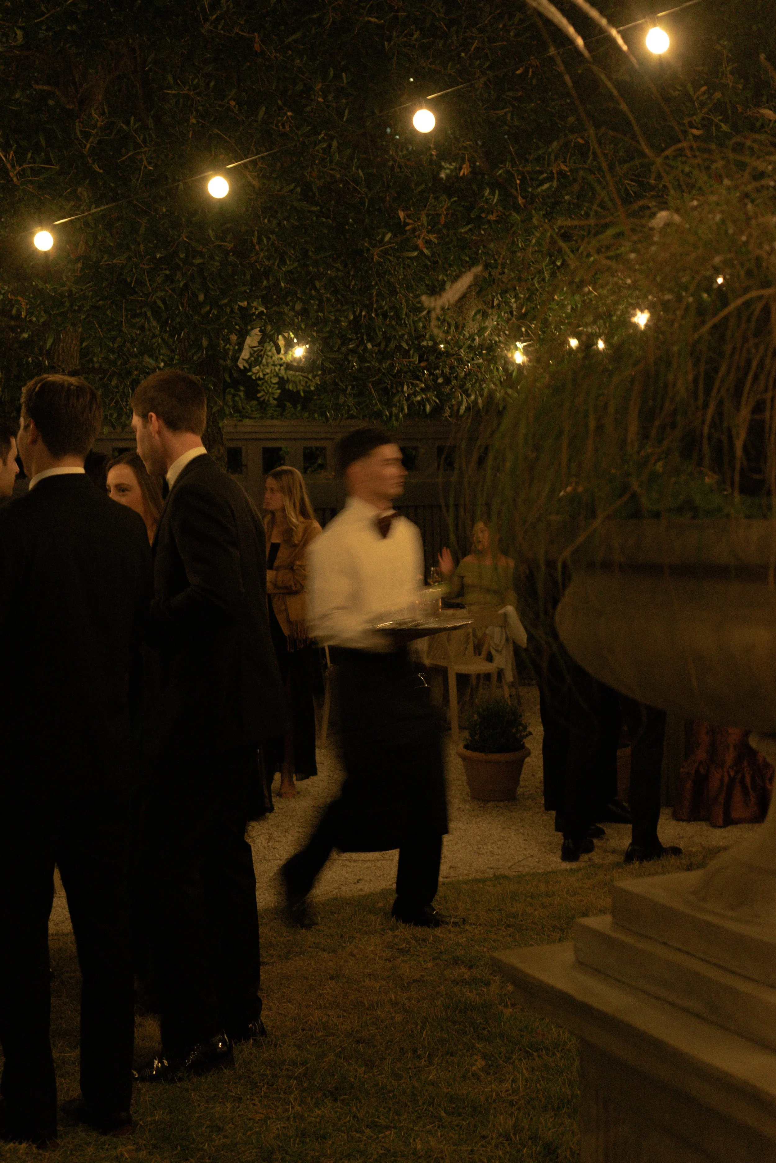 Guests mingle during an intimate evening wedding reception under warm lights at the Gibbes Museum, captured with a documentary editorial photography approach.