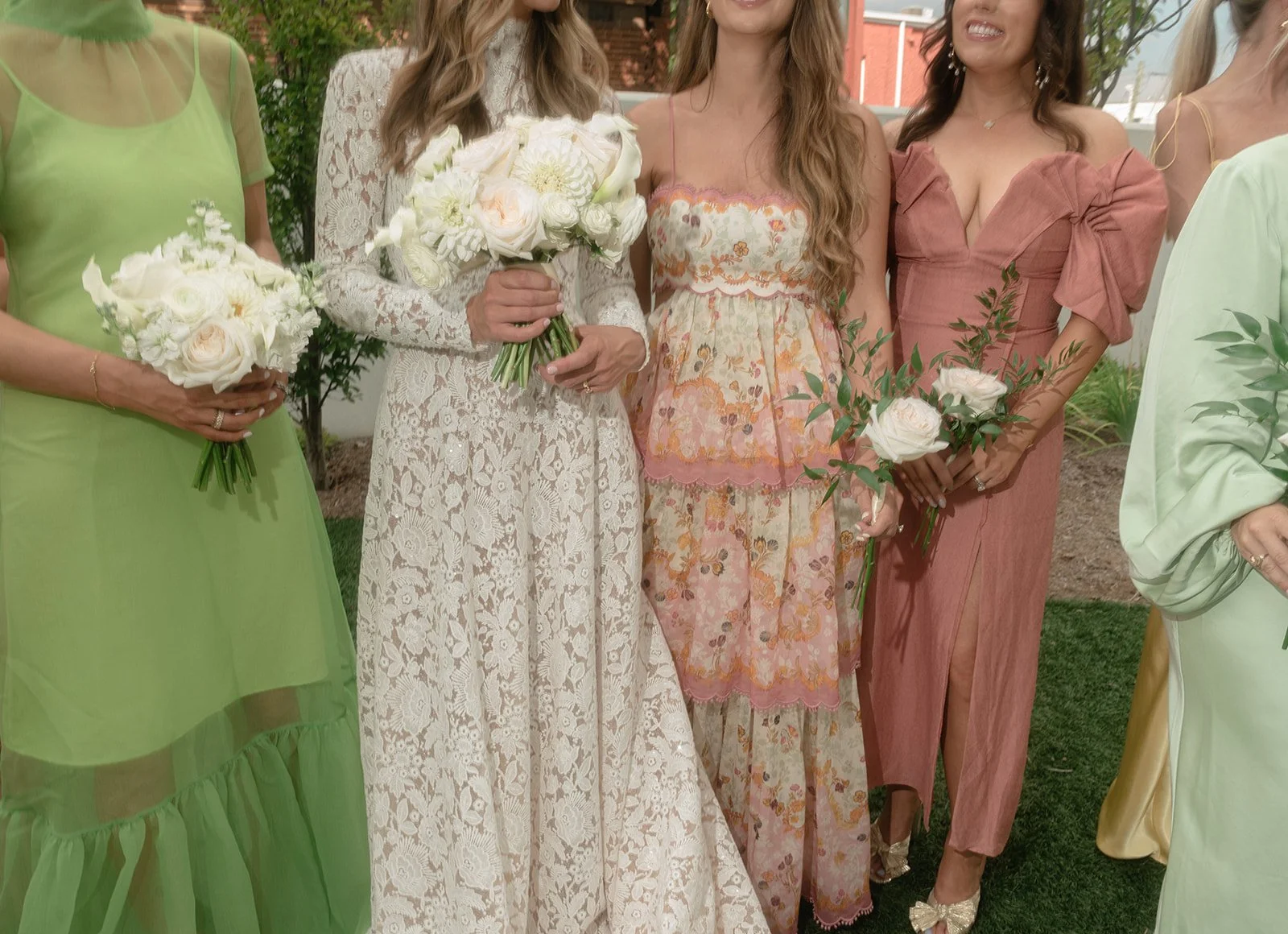 The bride mingles with her bridesmaids, who wear a bright and colorful mismatched but intentional array of dresses that serves the tropical color palette of the destination wedding.