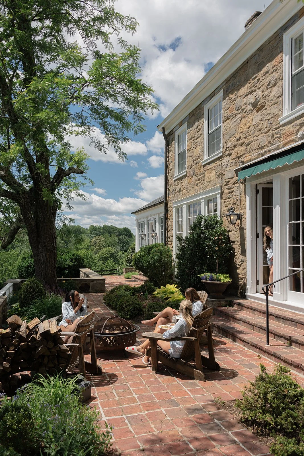 Bridesmaids have a relaxing morning outside the historic stone Manor House at Goodstone Inn beneath a blue spring sky.