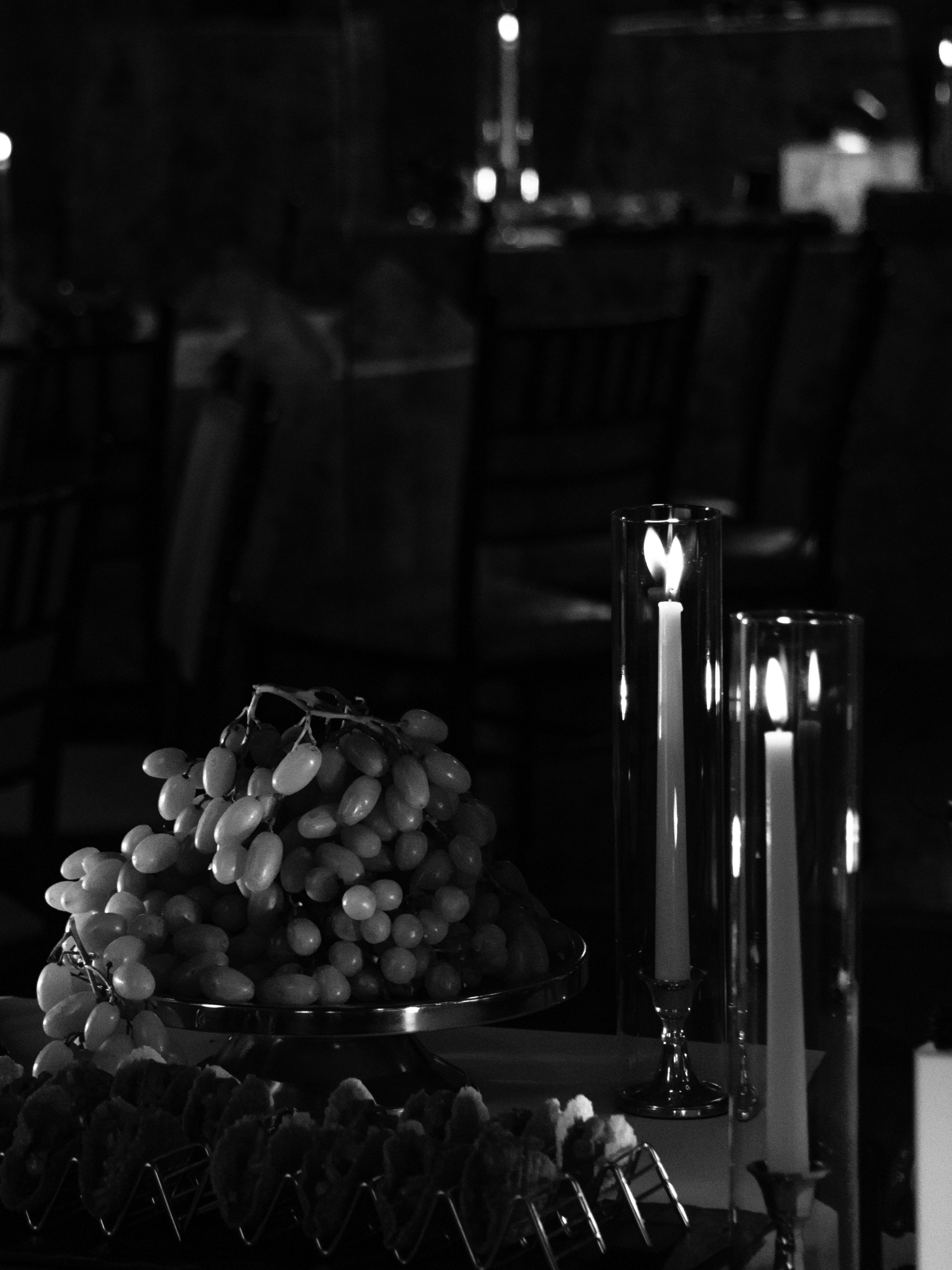 Moody black-and-white detail of the candlelit rehearsal dinner tablescape.