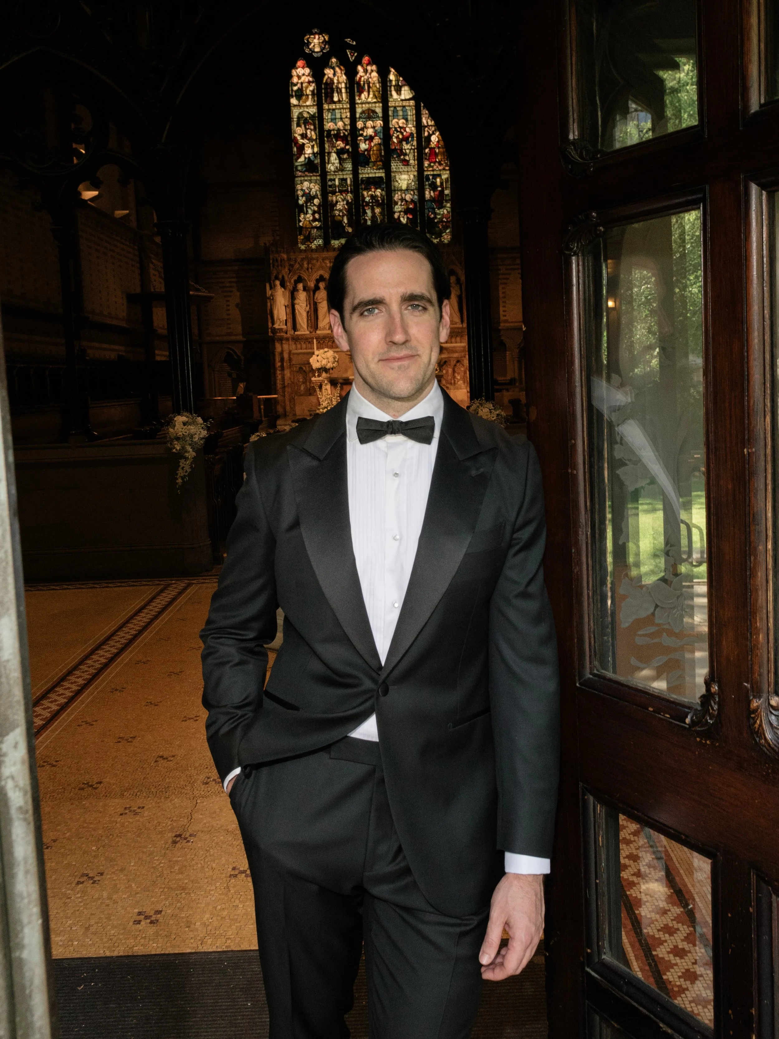 Black tie groom portrait photographed at the doors of the chapel during a luxury wedding celebration at Chelsea Square and the Highline Hotel in New York City.