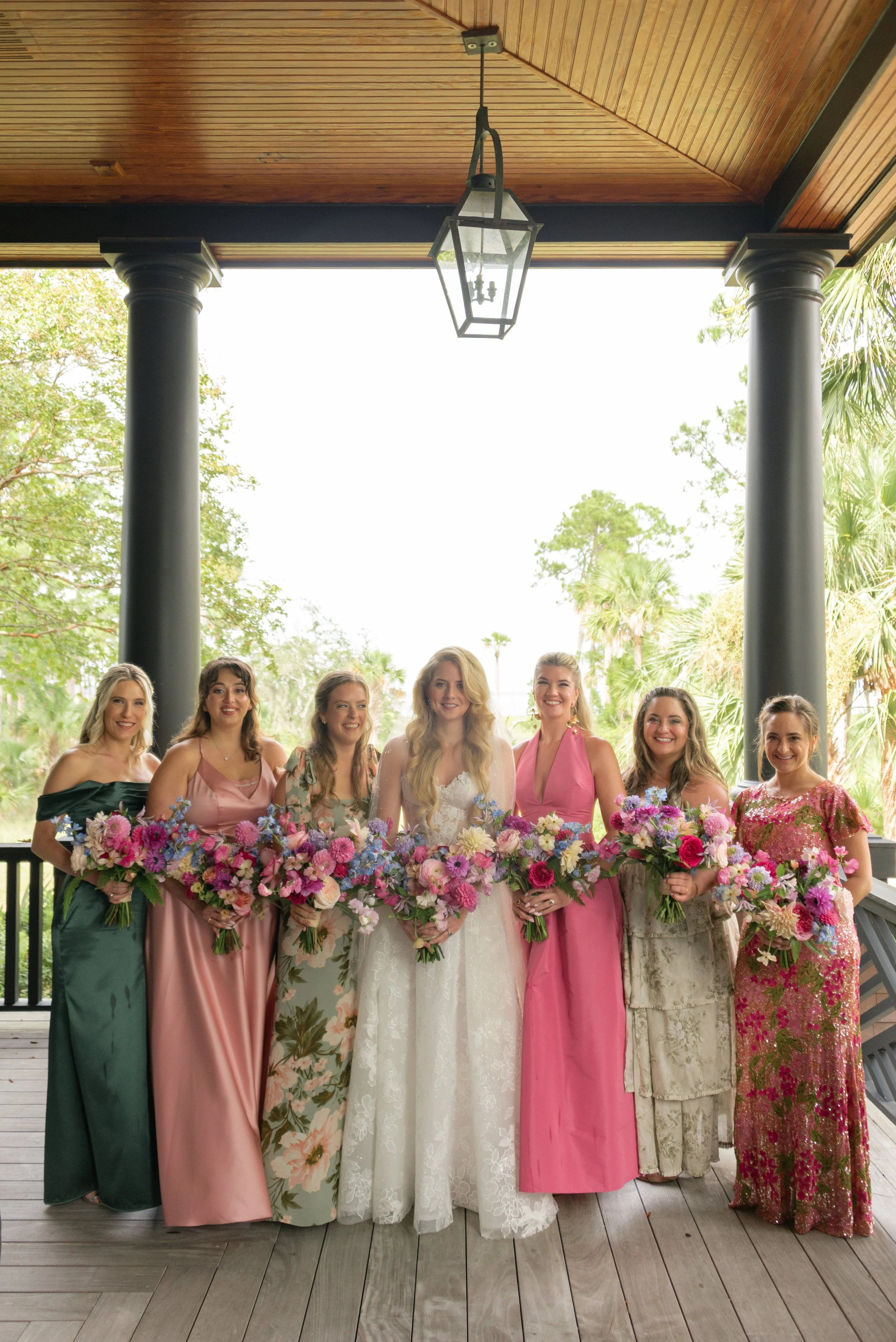 Katie and her bridesmaids hold colorful bouquets by Festoon on the porch before leaving for The Ocean Course ceremony.