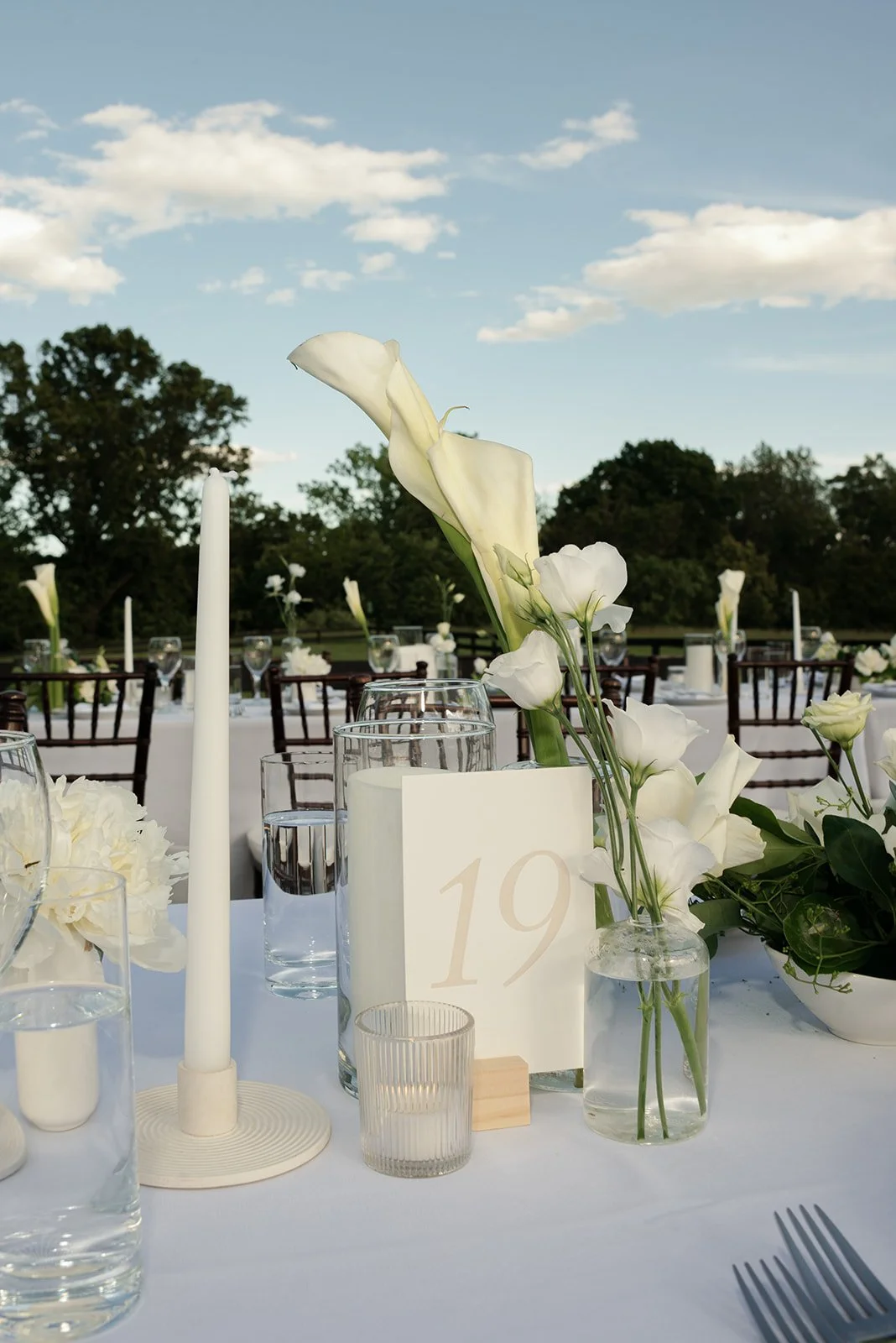 Ivory floral arrangement and table number displayed on a long outdoor reception table at Goodstone Inn.