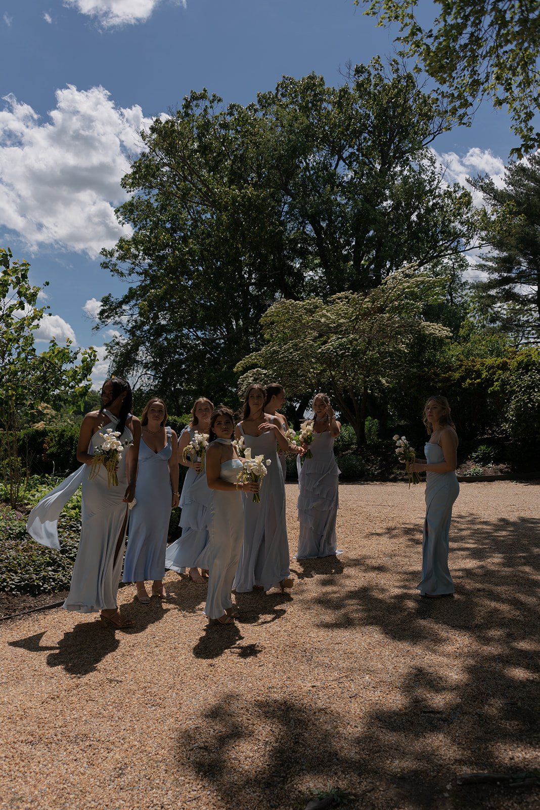 Bridesmaids walking across the lawn at Goodstone Inn beneath a bright blue spring sky.
