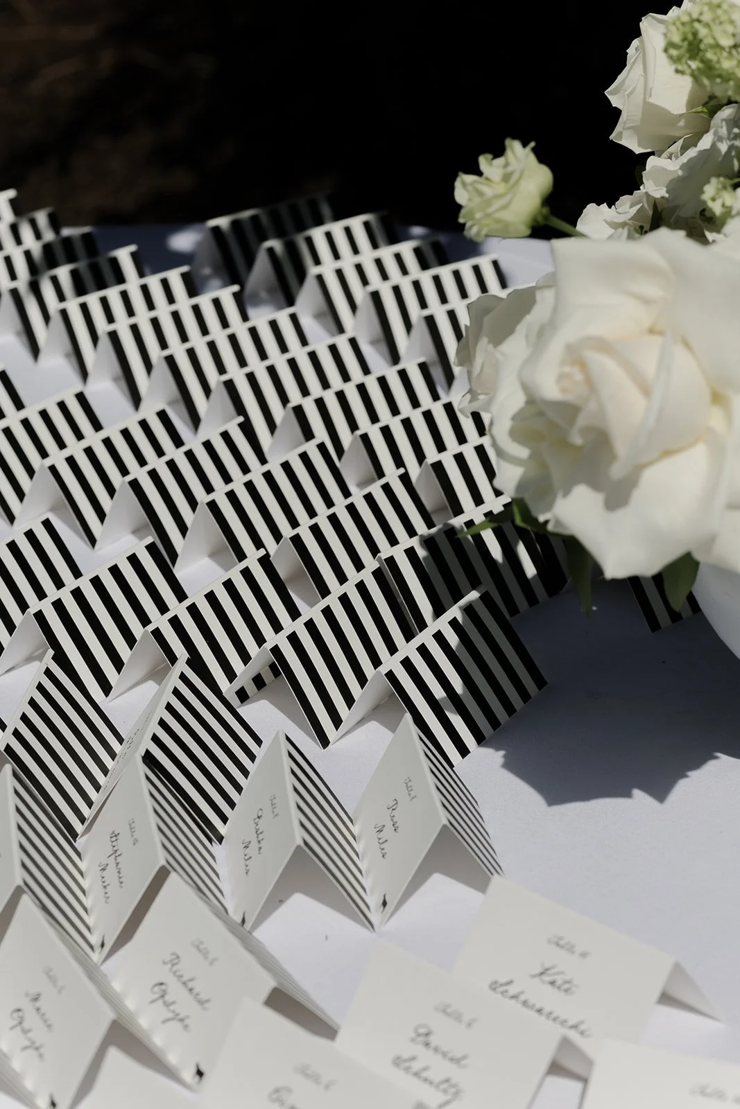 Striped escort cards and white garden roses arranged together in bright sunlight at Goodstone Inn.