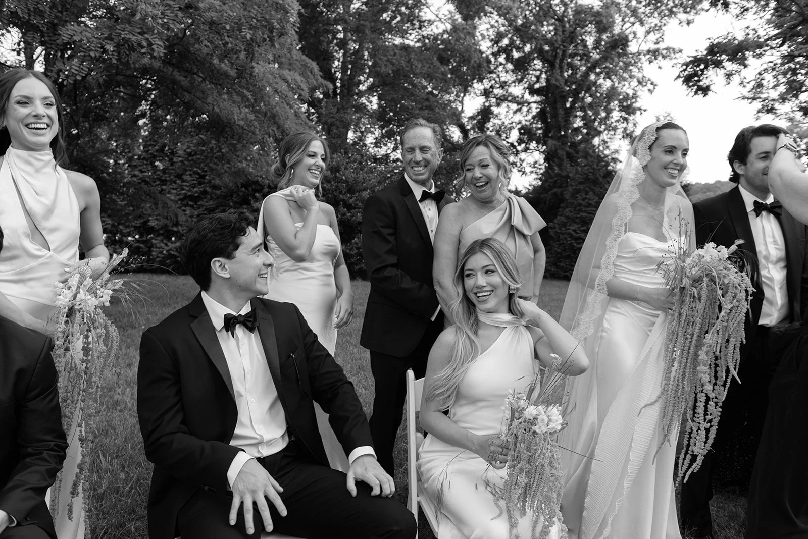 Black and white editorial wedding party portrait featuring the couple and friends, capturing personality, connection, and the human moments behind the celebration.