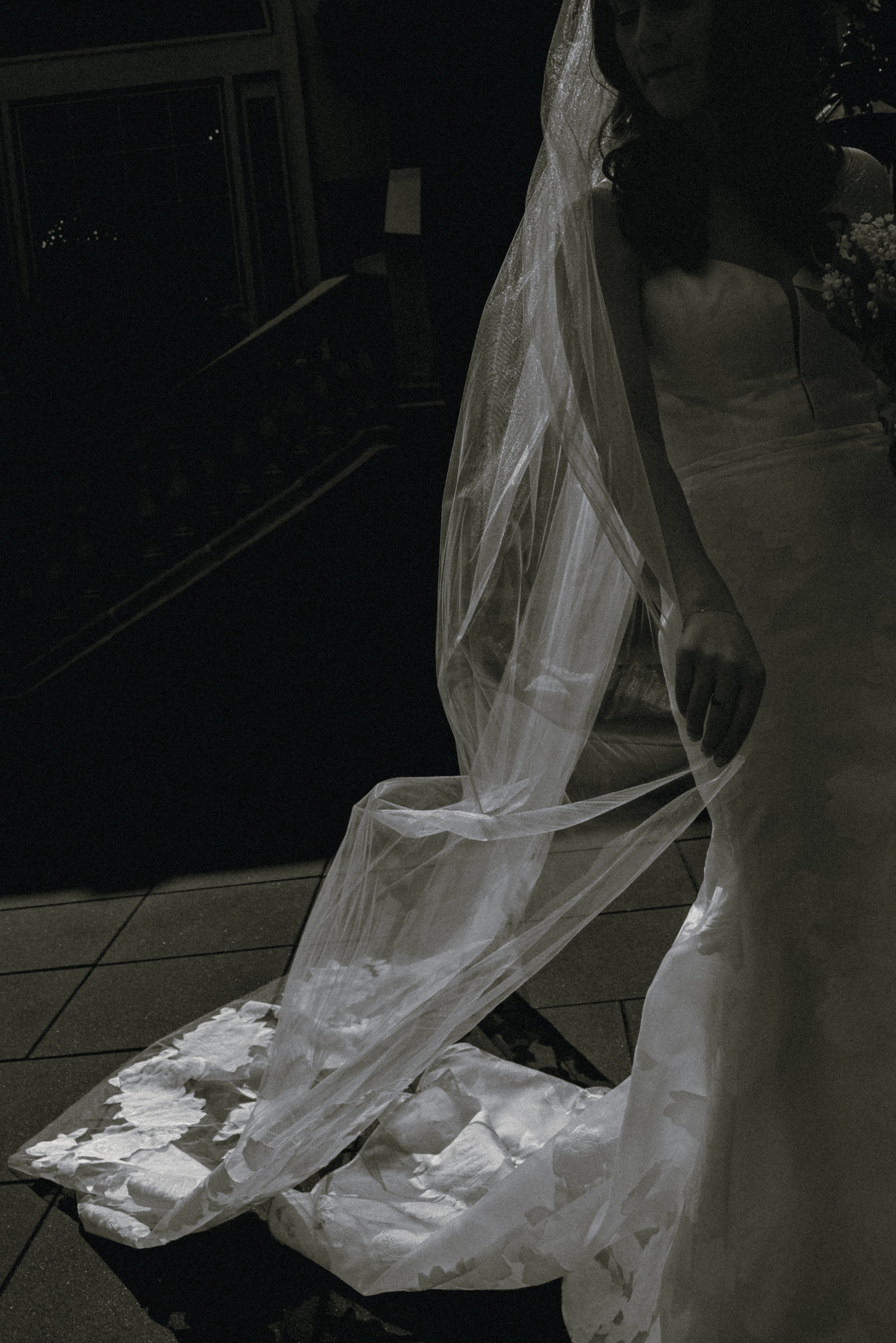 A wedding gown and flowing lace train in a quiet black-and-white bridal portrait.