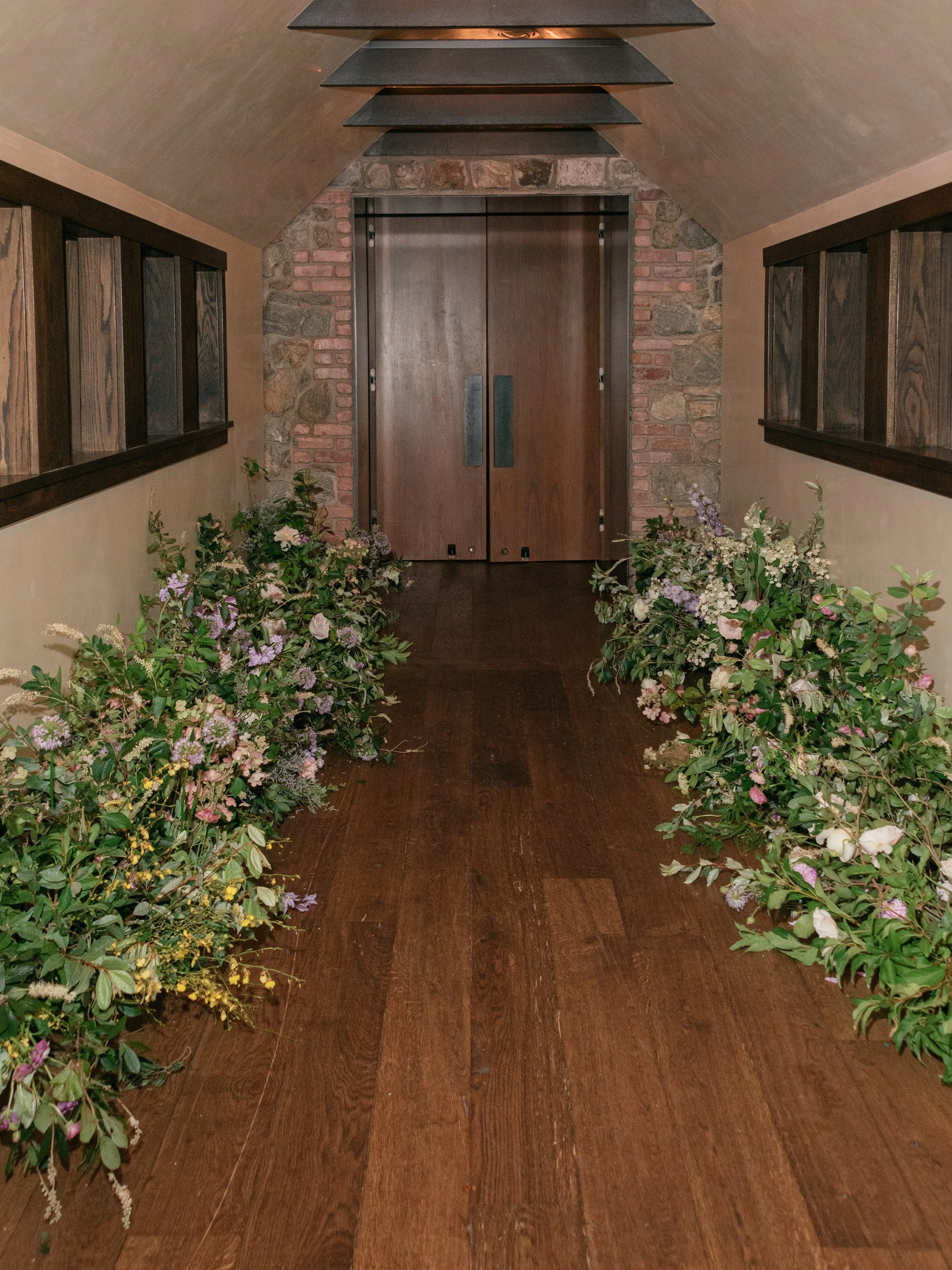 Hallway transformed with abundant garden-inspired florals by Mudari Creative for Jennie and Will’s wedding.