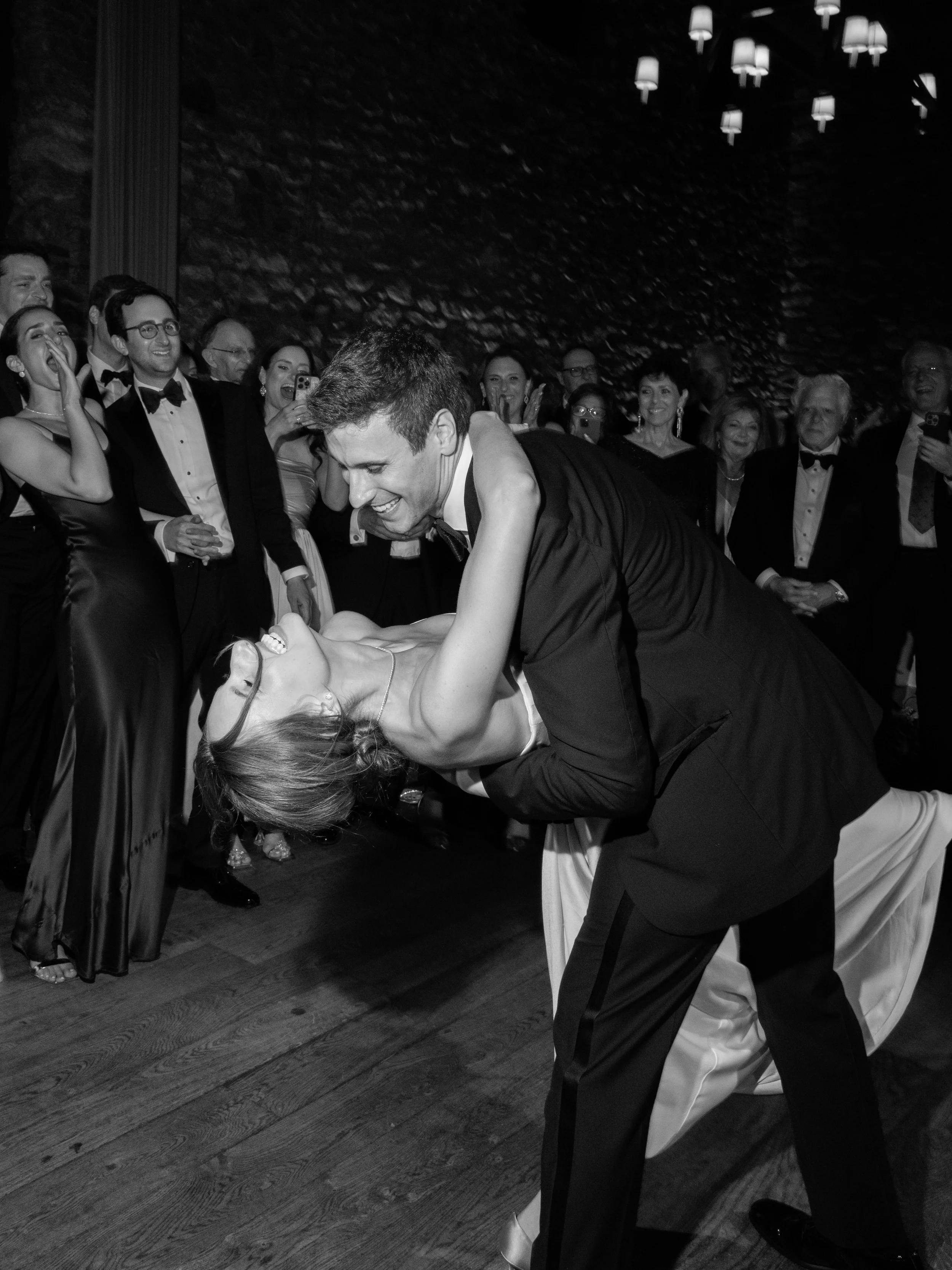 Black-and-white candid of Jennie and Will surrounded by guests on the reception dance floor.