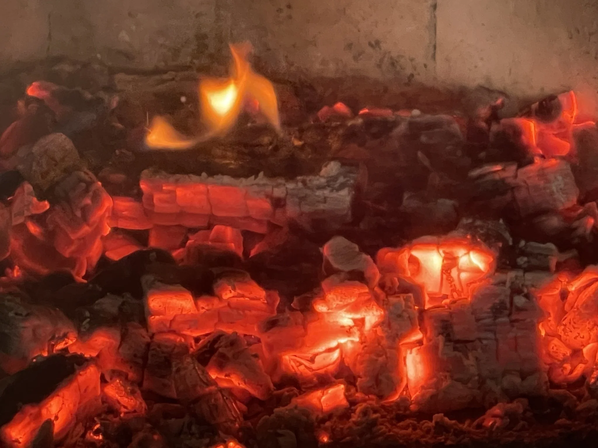 Glühende Holzscheite in einem offenen Kamin, flackerndes Feuer