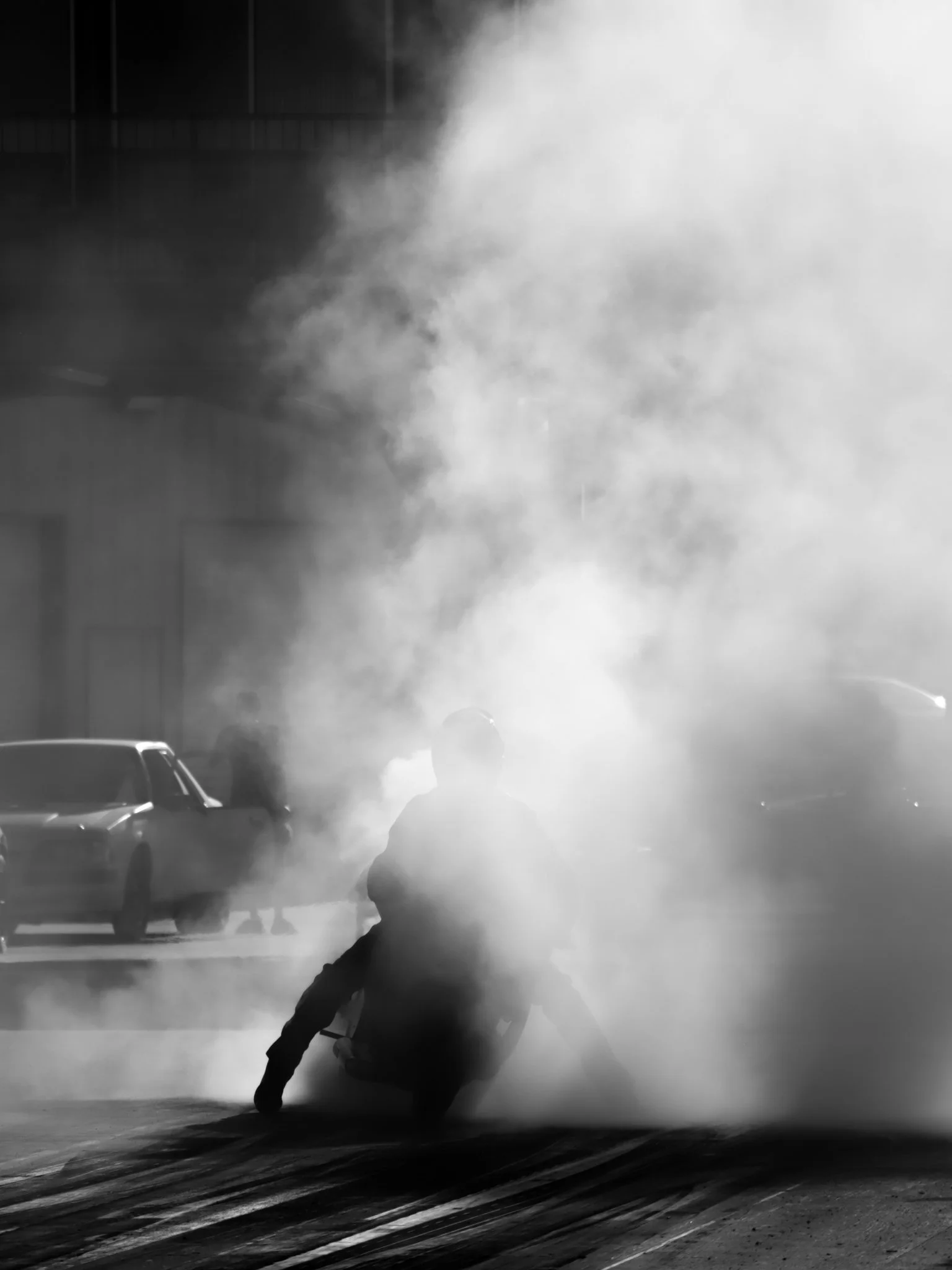 Black and white picture of a motorcycle doing a burnout on a dragstrip lane