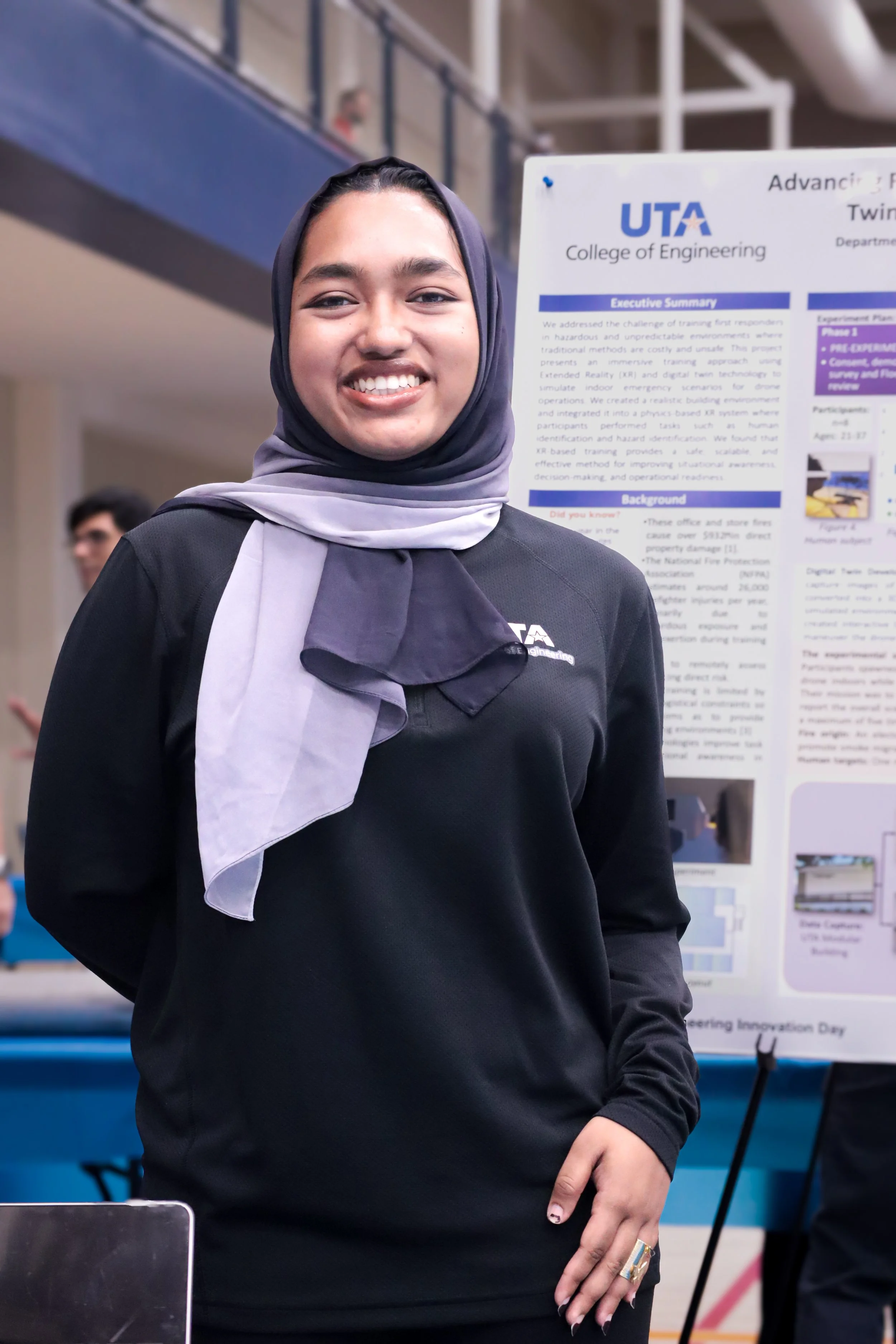 A female engineering student at a college event pictured with their project