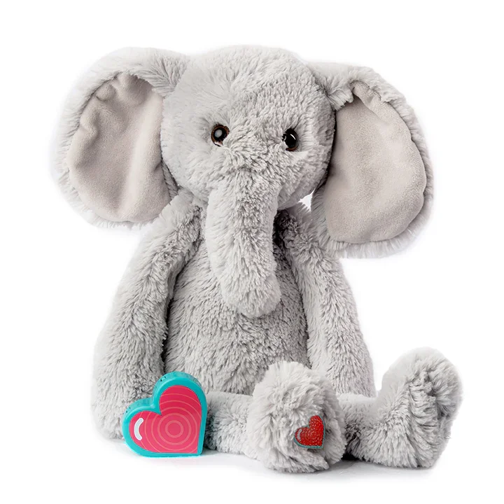 A plush gray elephant stuffed animal with large floppy ears, sitting with a pink and blue heart-shaped object and a smaller red heart on its front paw.