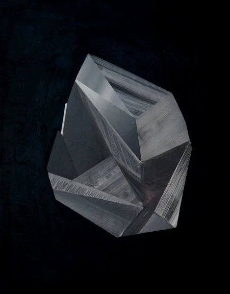 A metallic geometric sculpture resembling a distorted cube with reflective surfaces, set against a black background.